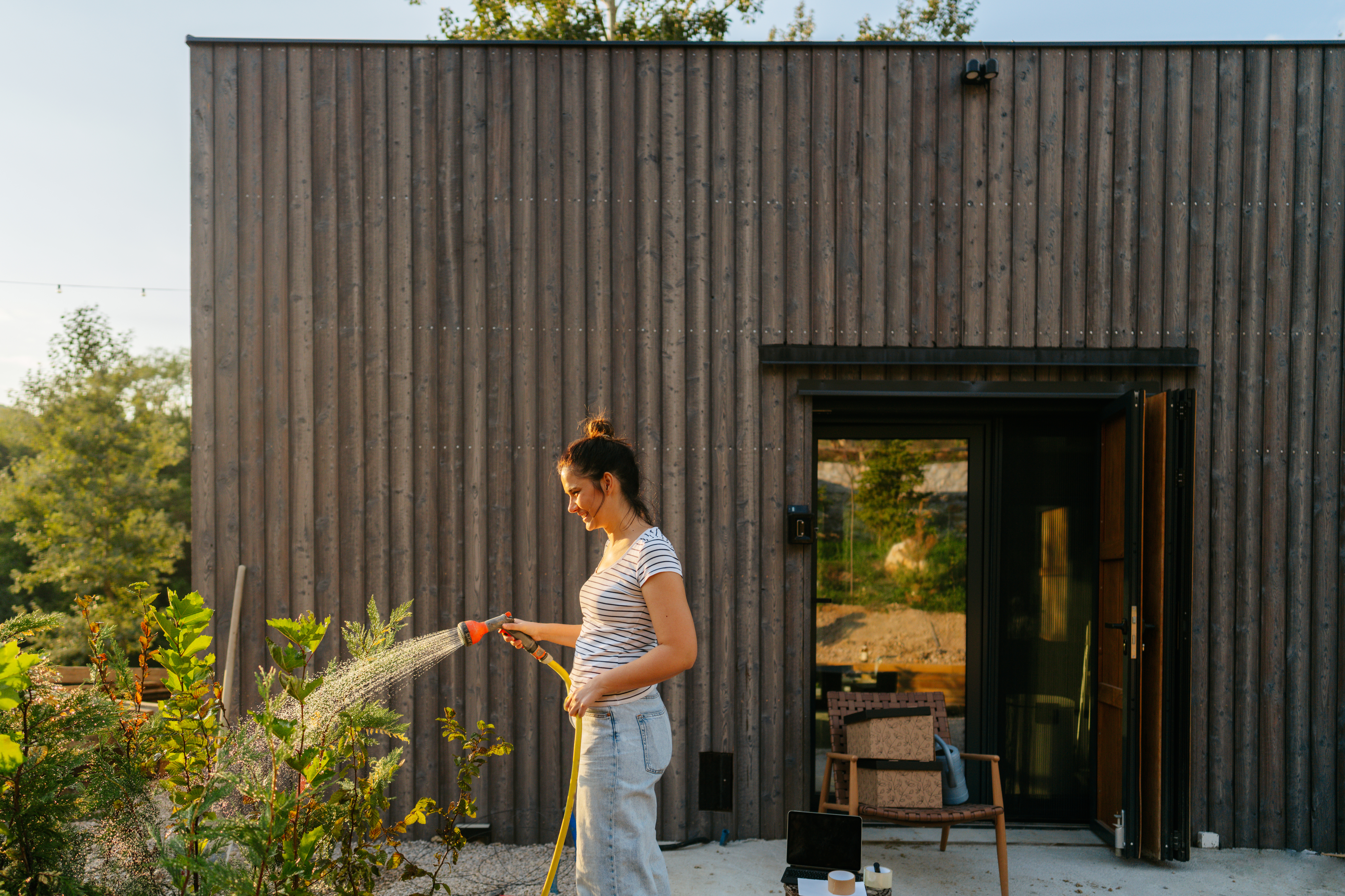 A woman watering her garden in front of her house