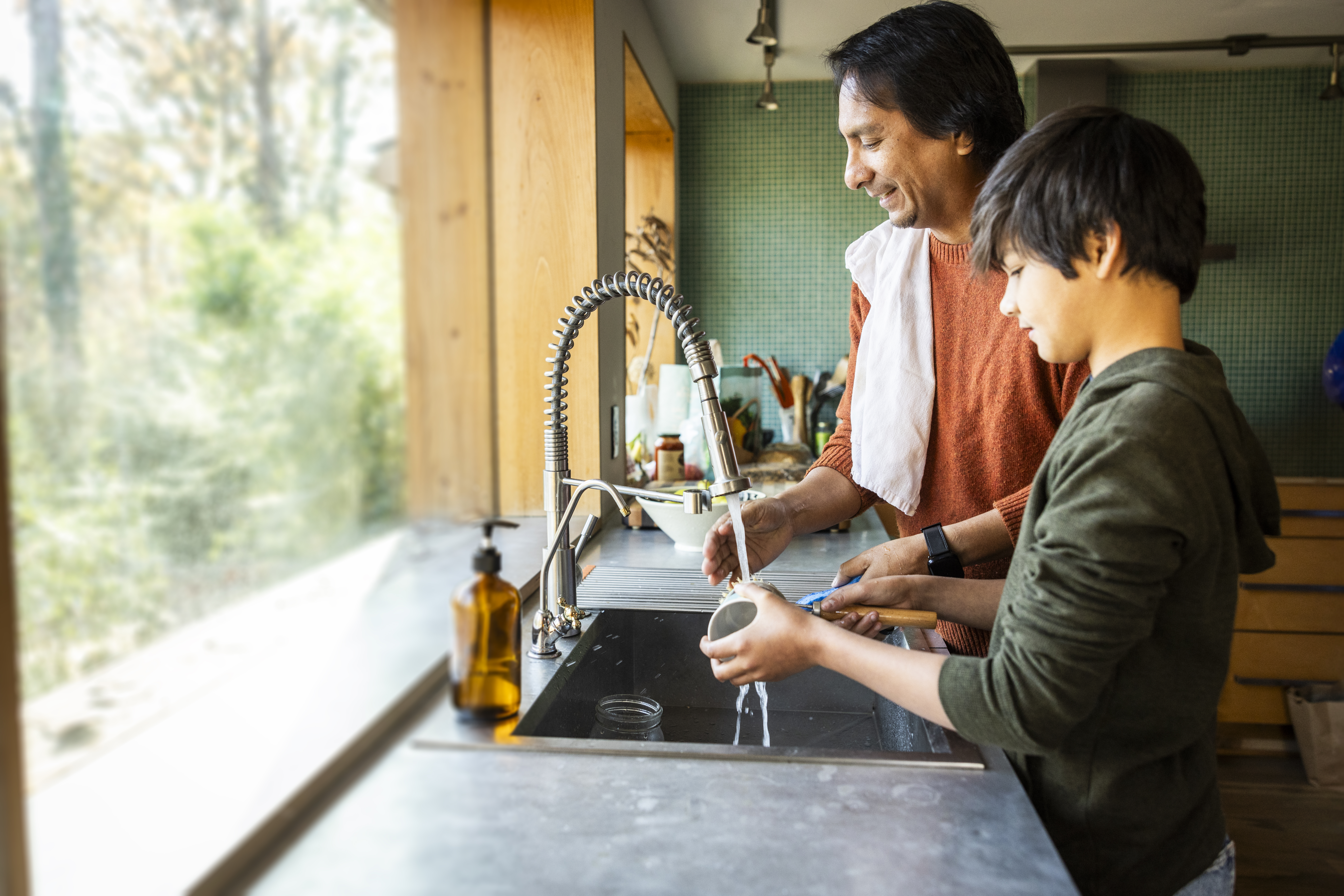 Father and teenage son washing dishes