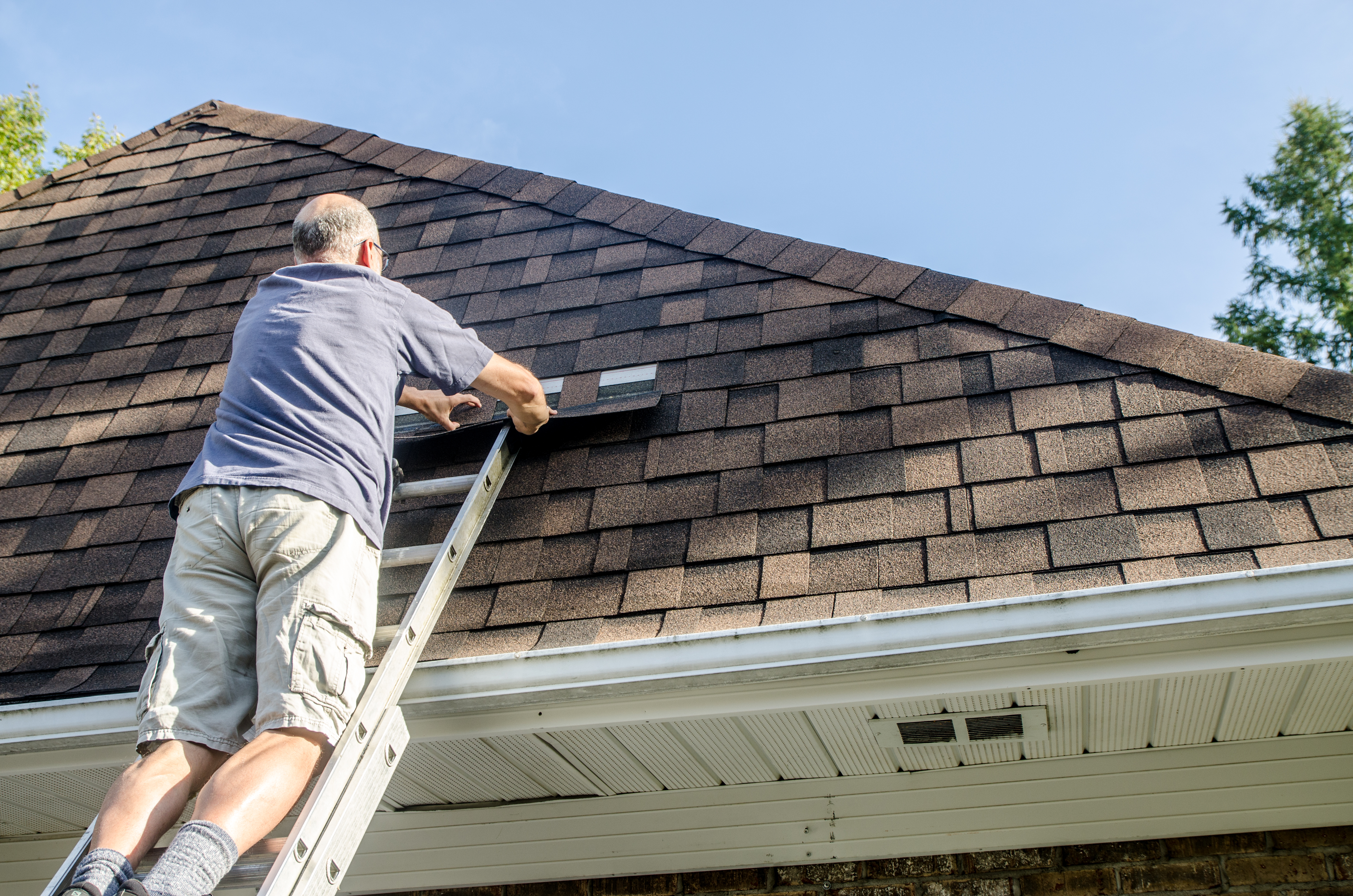 man repairing asphalt shingle roof