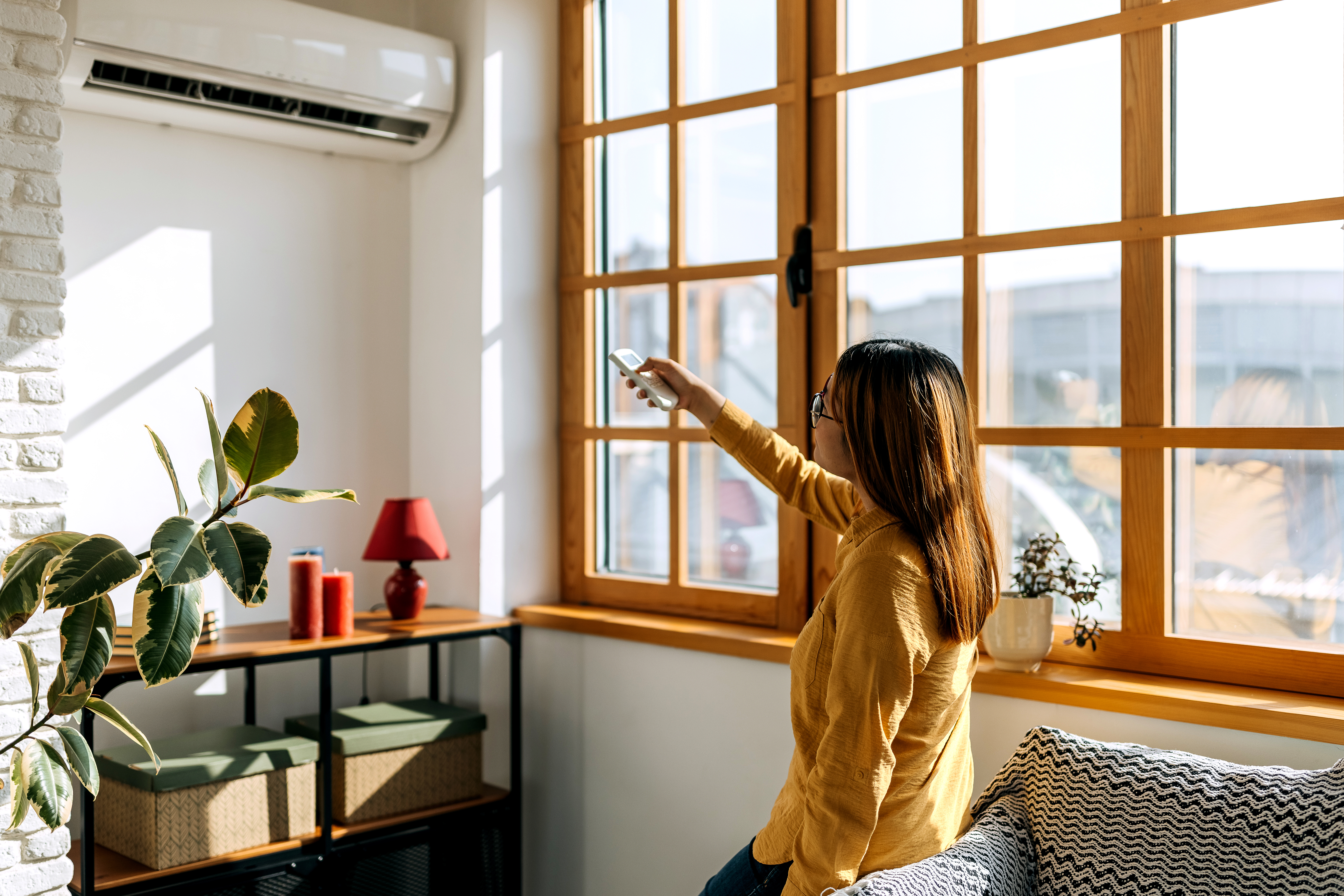 Woman using the remote to adjust the temperature on the AC