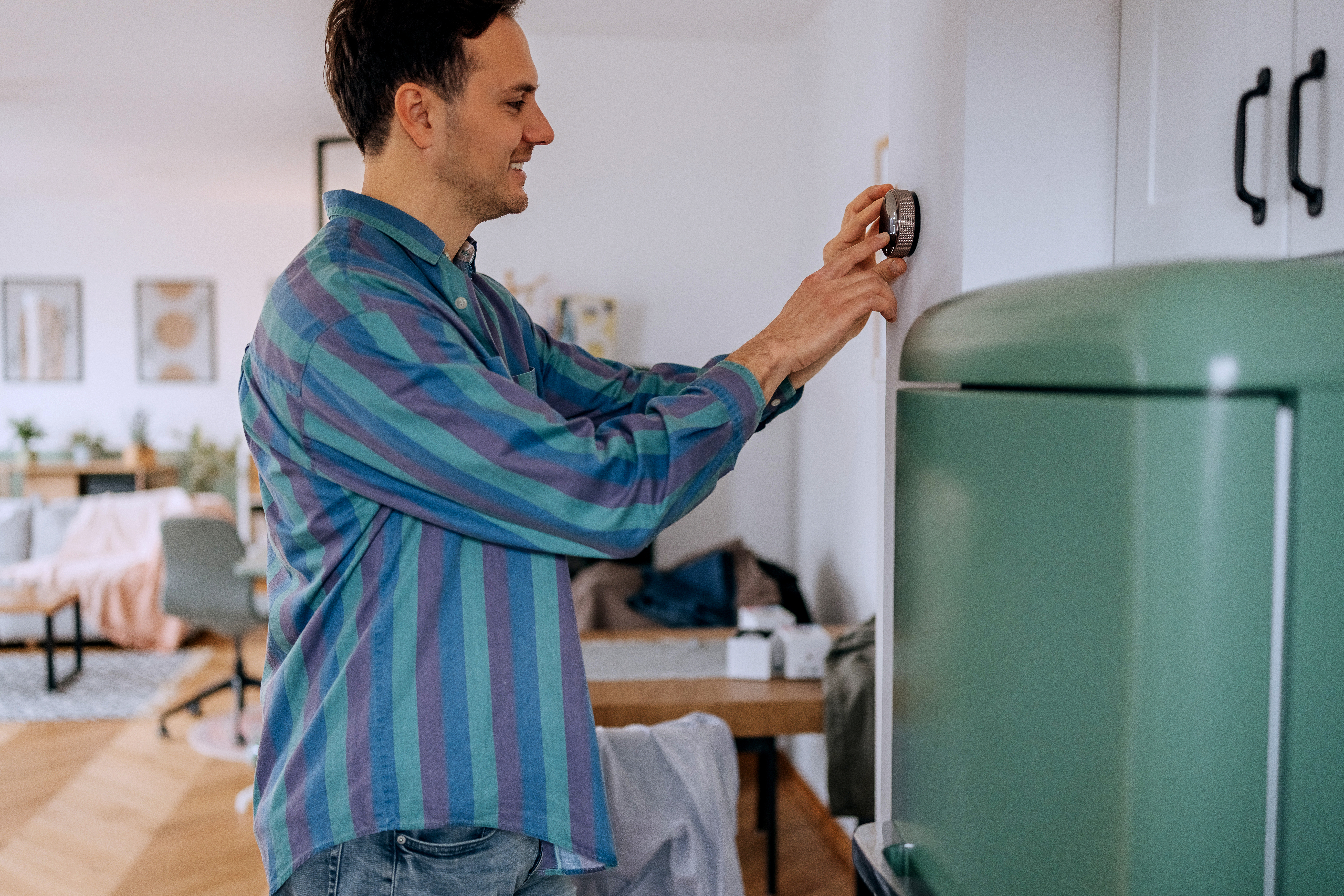 Man using a smart thermostat to adjust the AC temperature