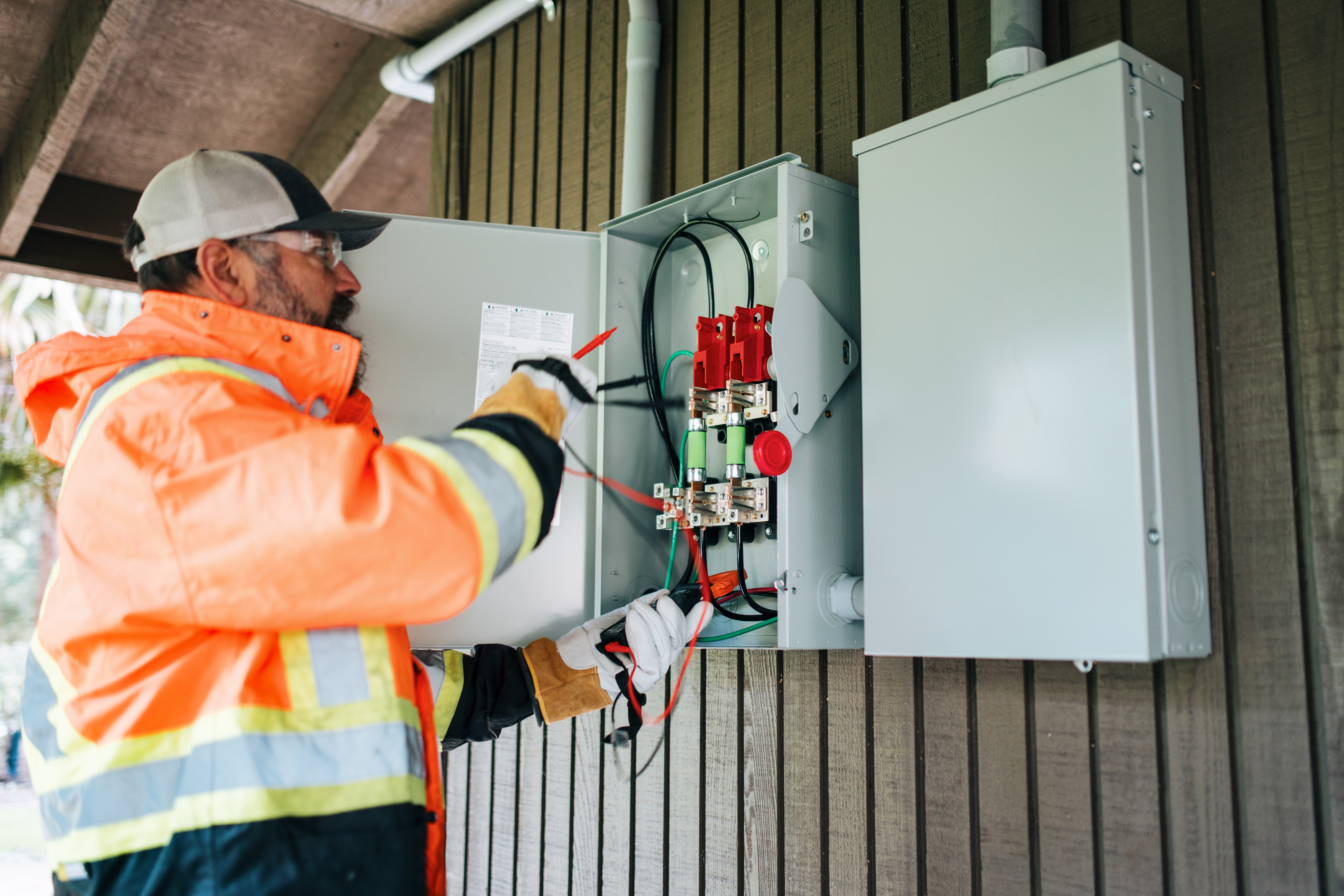 Electrician installing the electrical box outside the house  