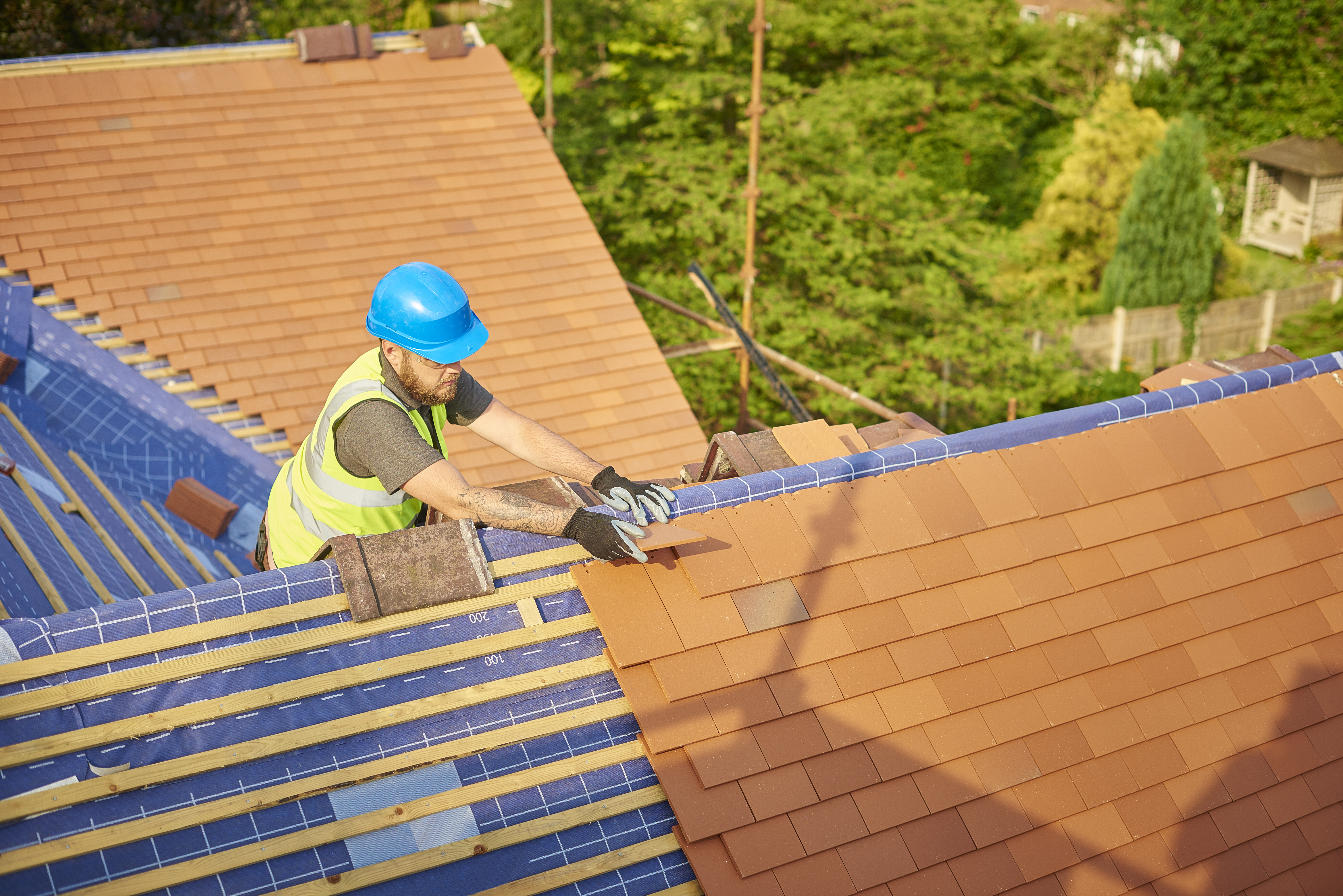 A roofer installing new clay tiles on a house 
