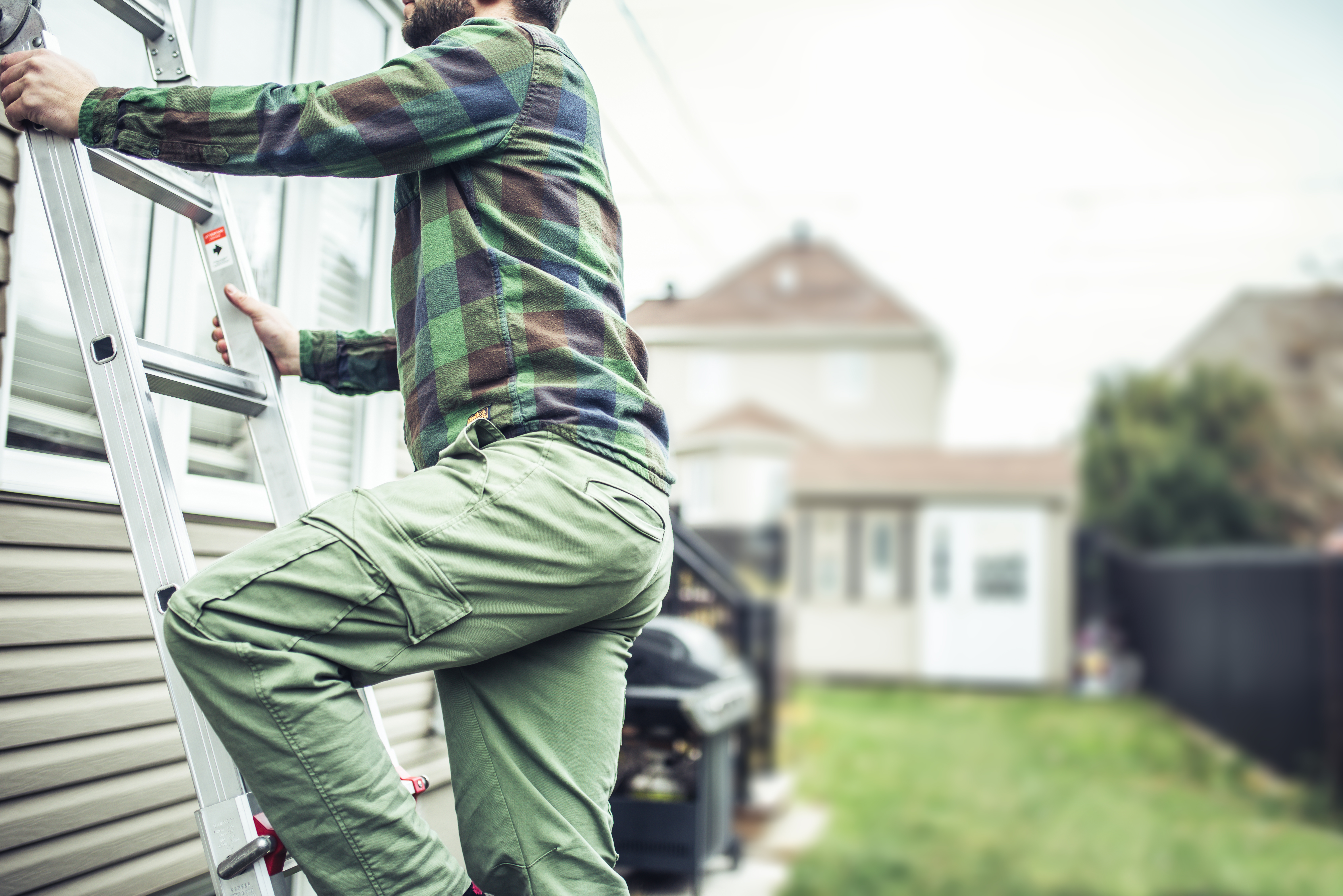 Repairman climbing the ladder to inspect the house
