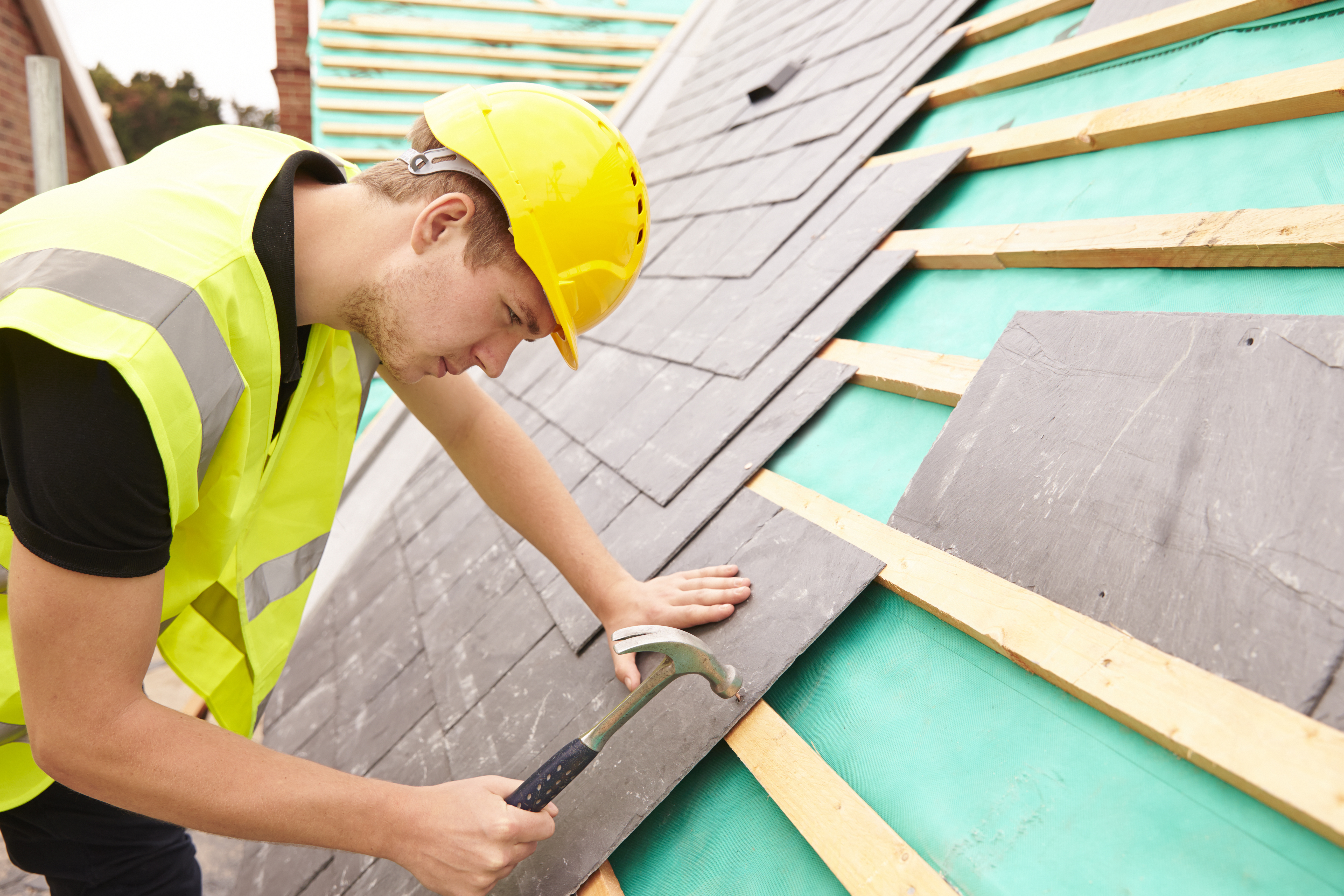 Worker installing slate shingles on the roof