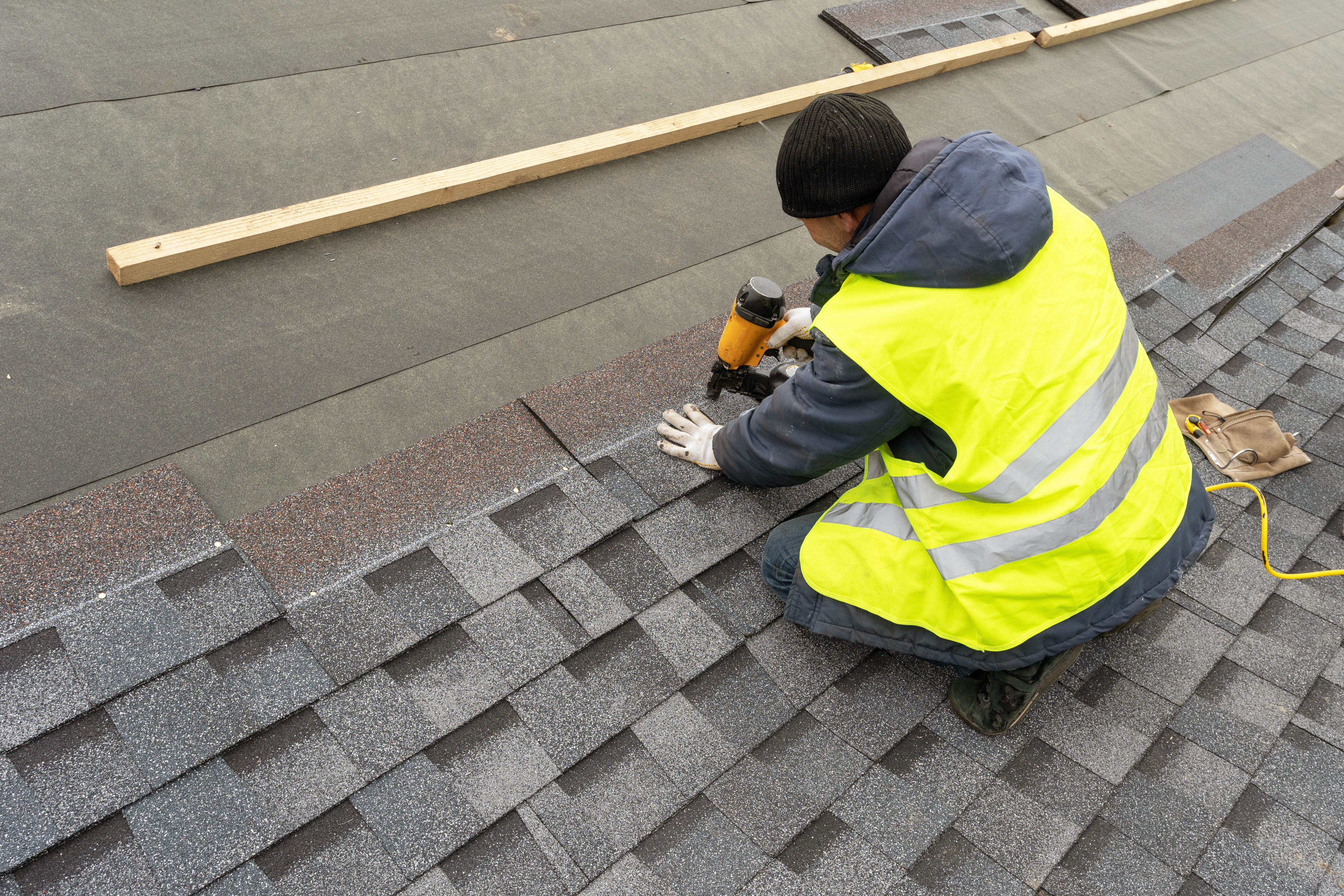Contractor installing asphalt shingles on the roof