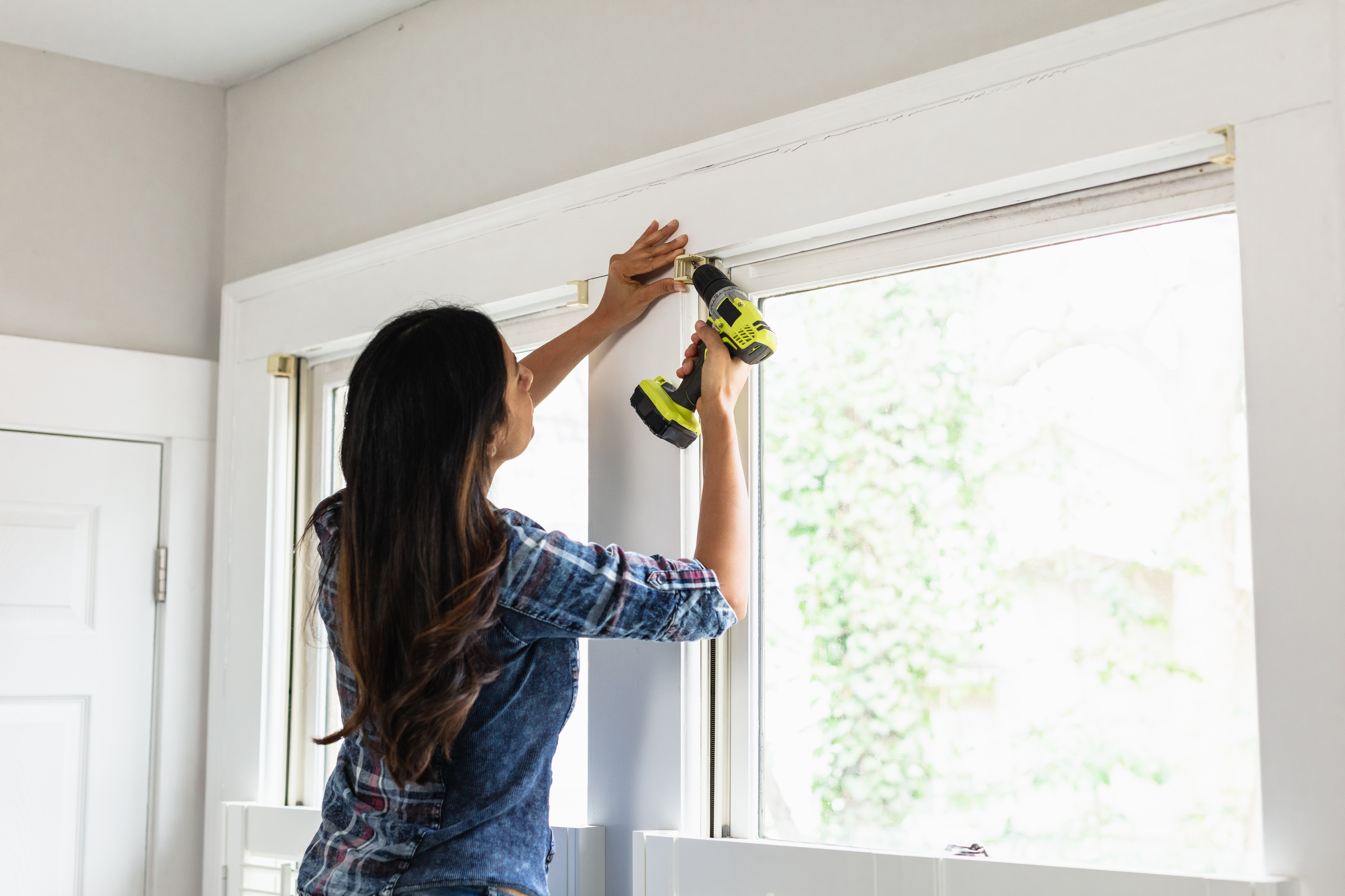 woman installing blinds in living room