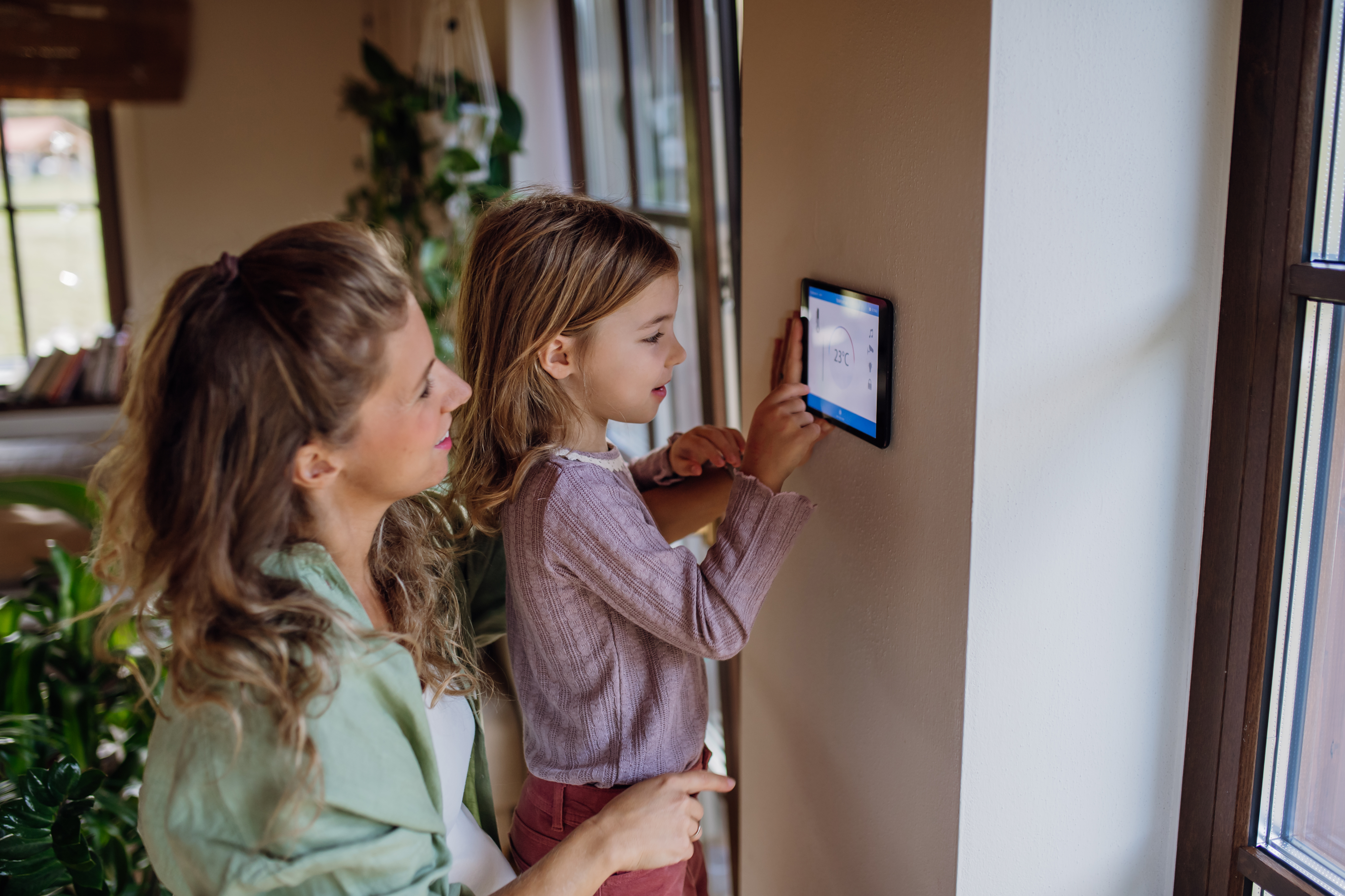Mother and daughter adjusting thermostat