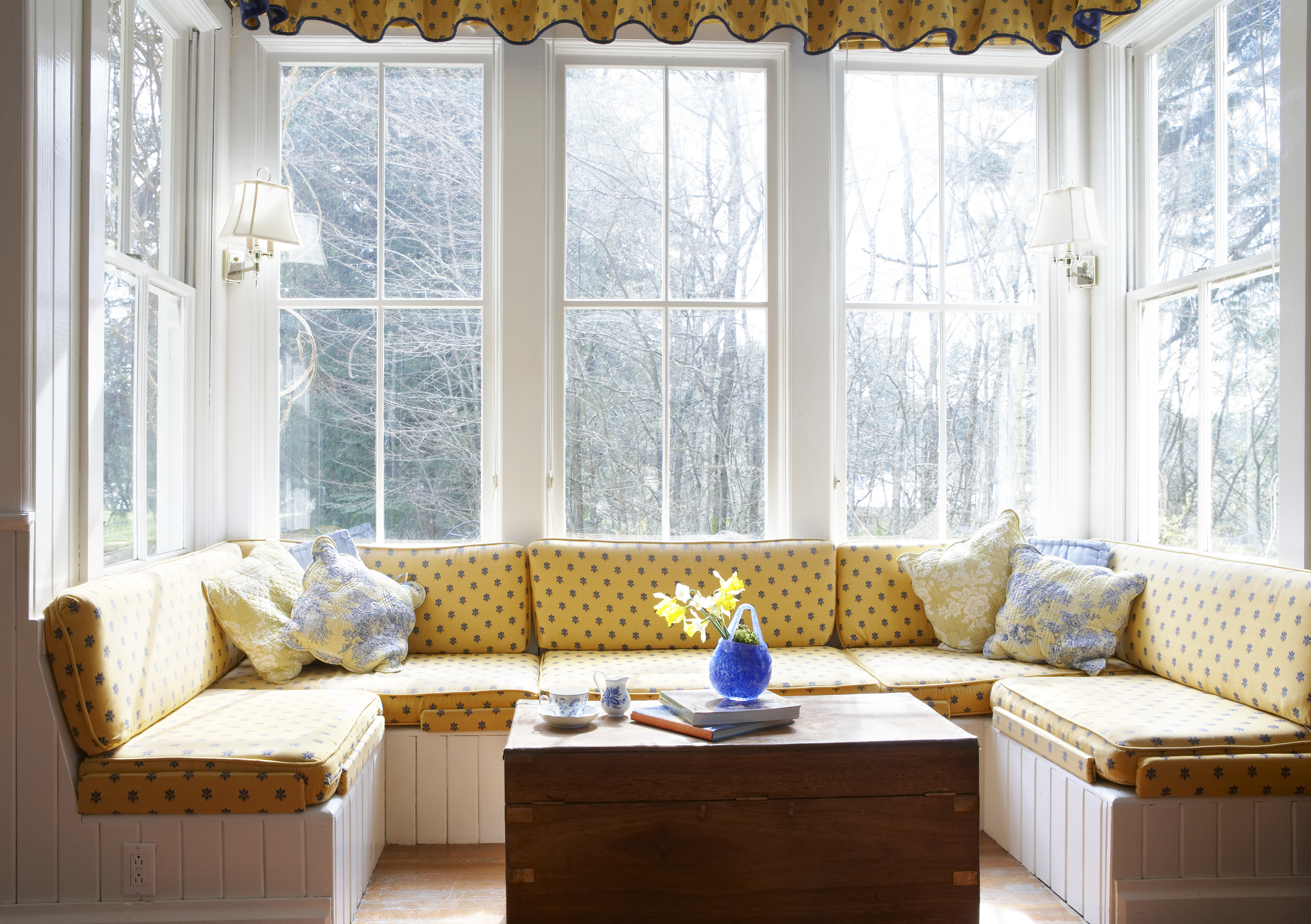 Cozy window nook with yellow cushions and a coffee table