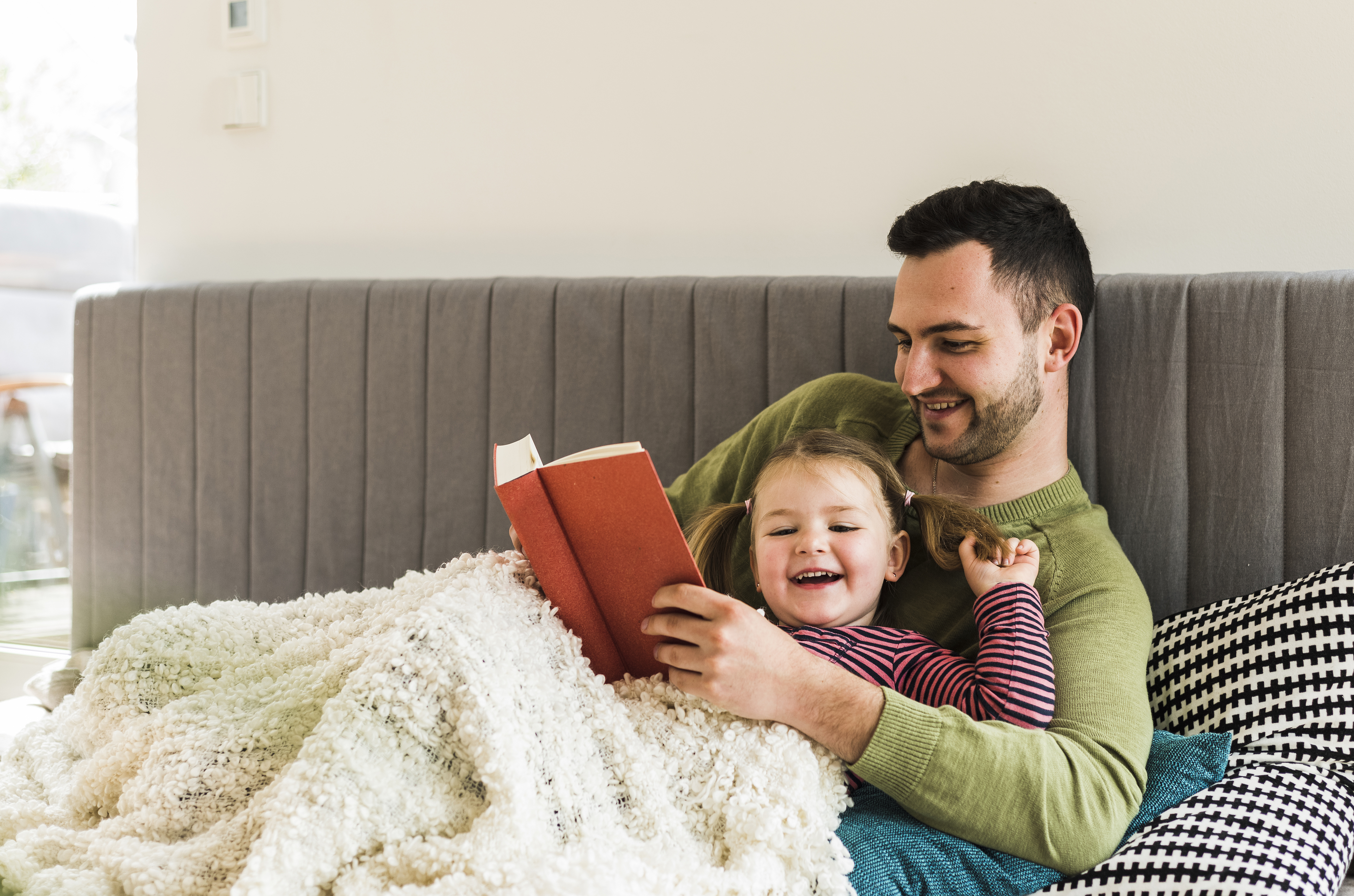 Father and daughter snuggling on the couch and reading a book  