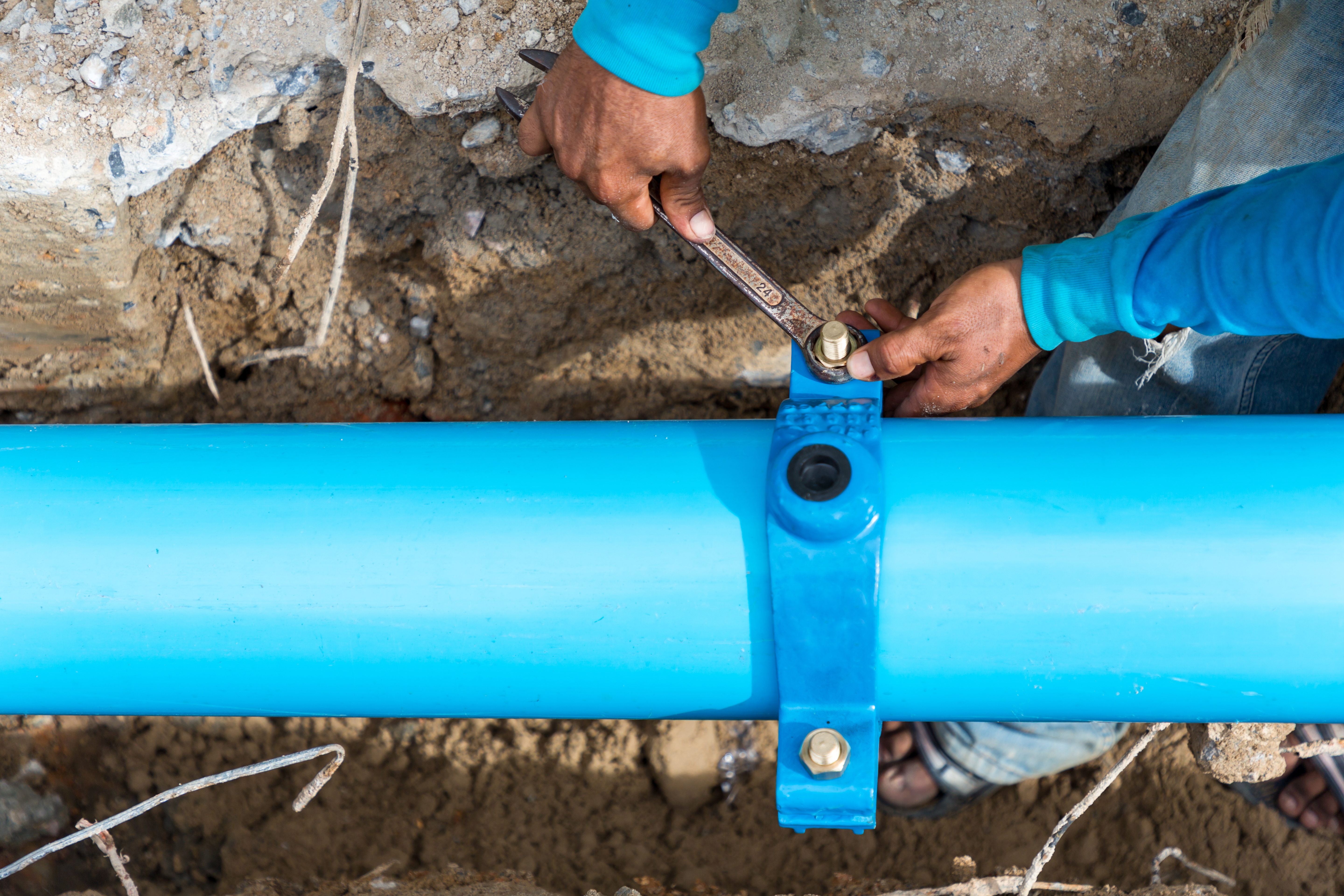 Man using a large wrench on water pipes