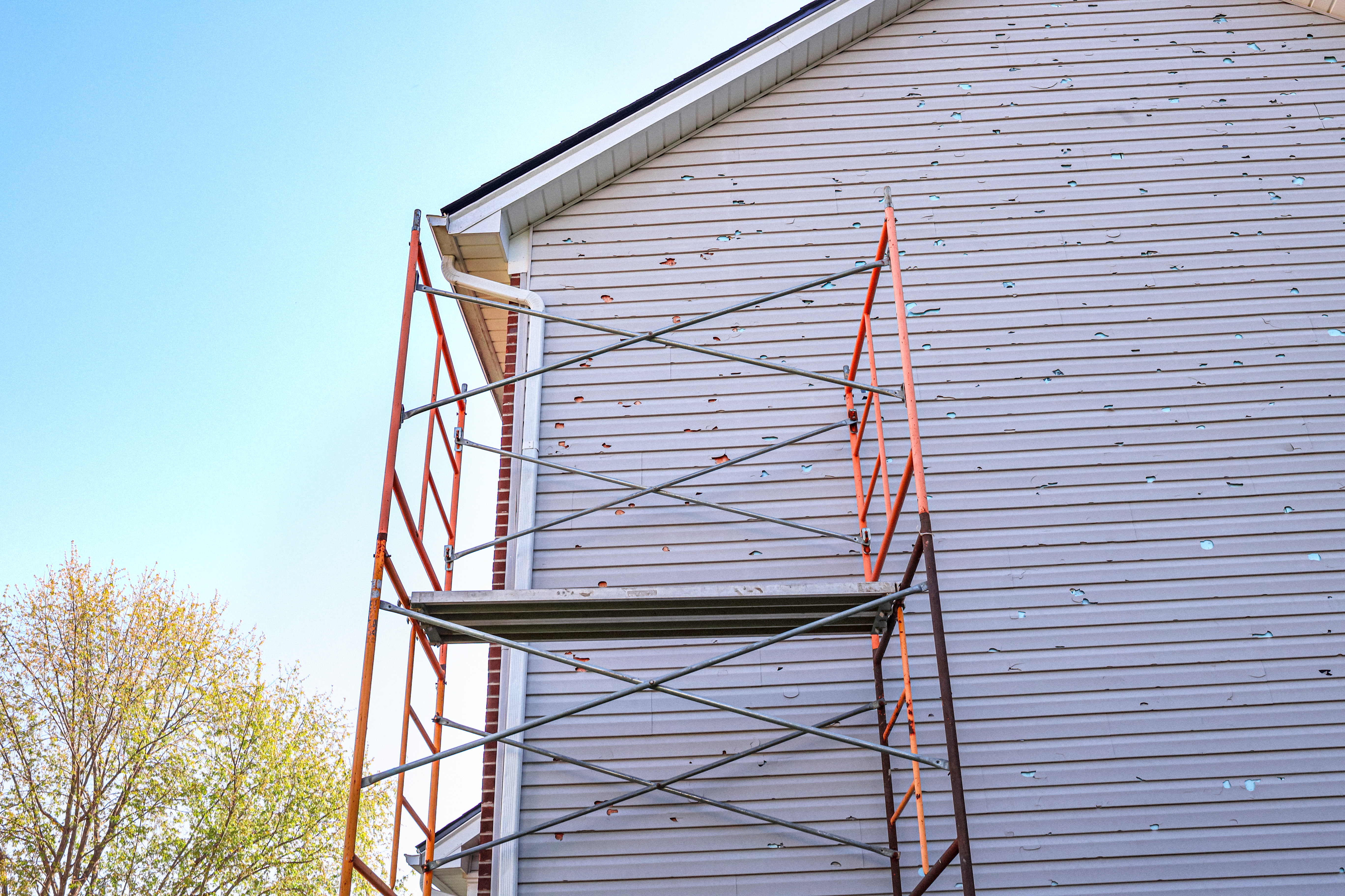A scaffold placed on the side of a house to repair the siding