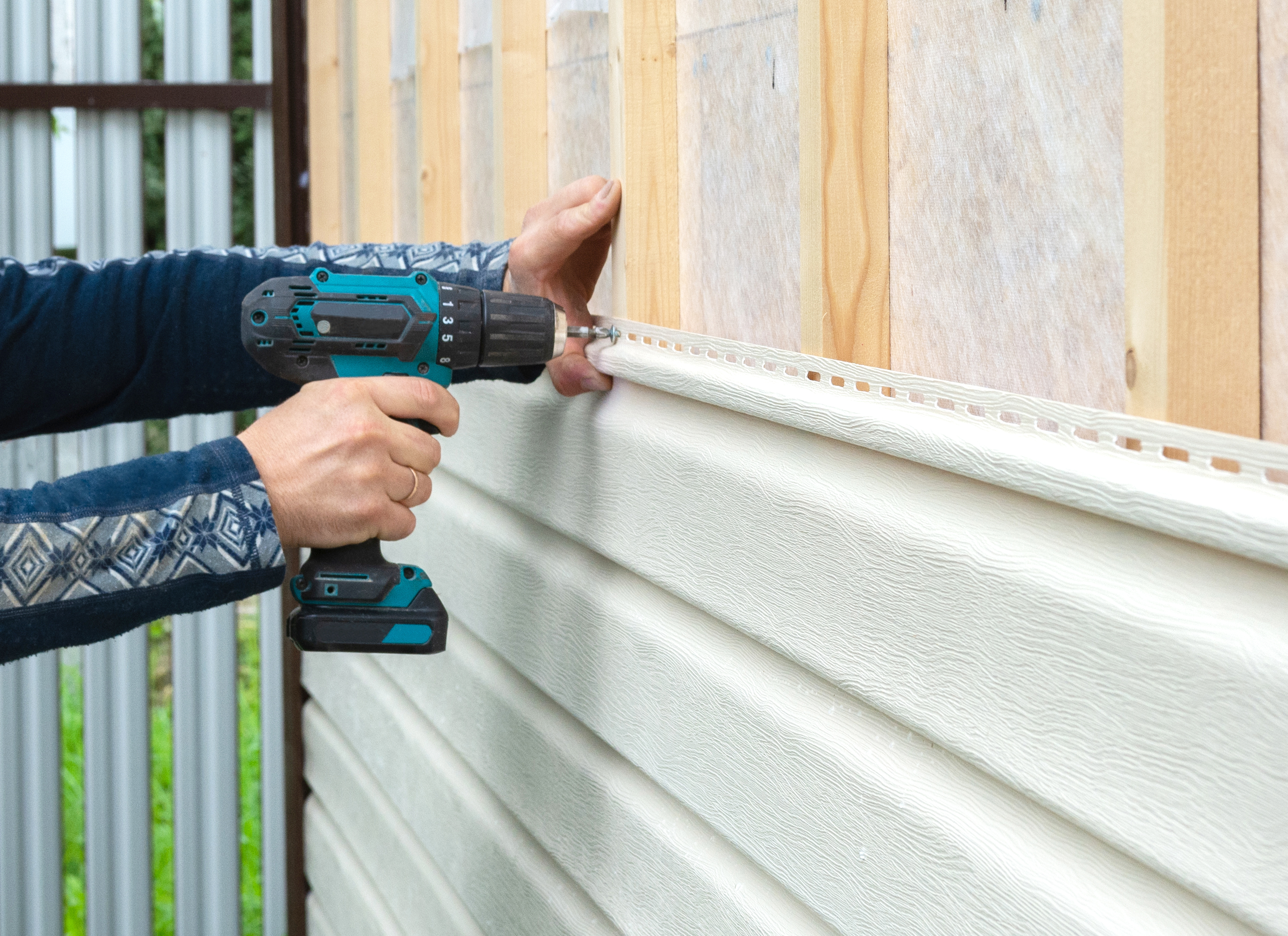Worker attaching new vinyl siding to the house