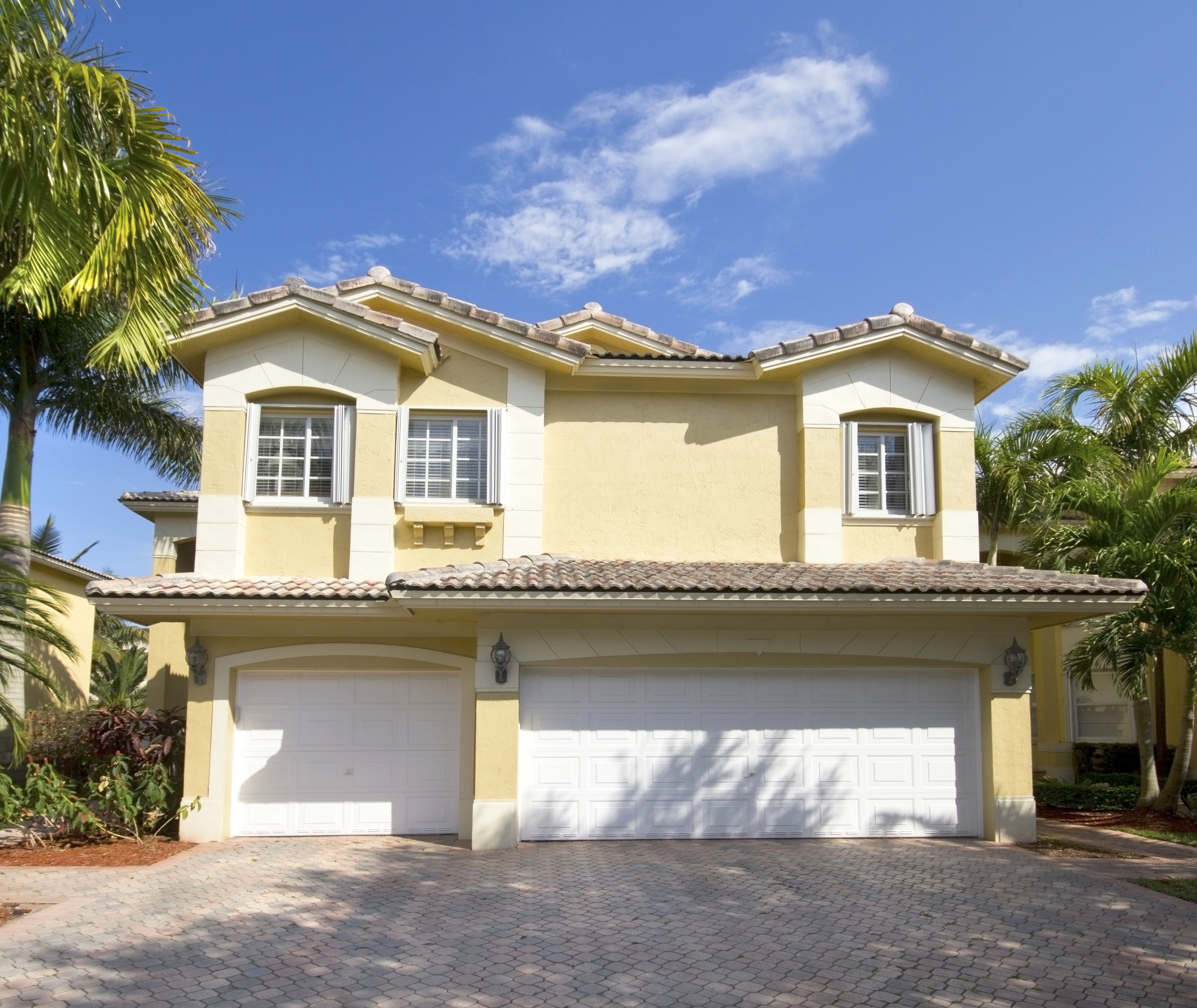 Coastal house exterior with a garage and palm trees