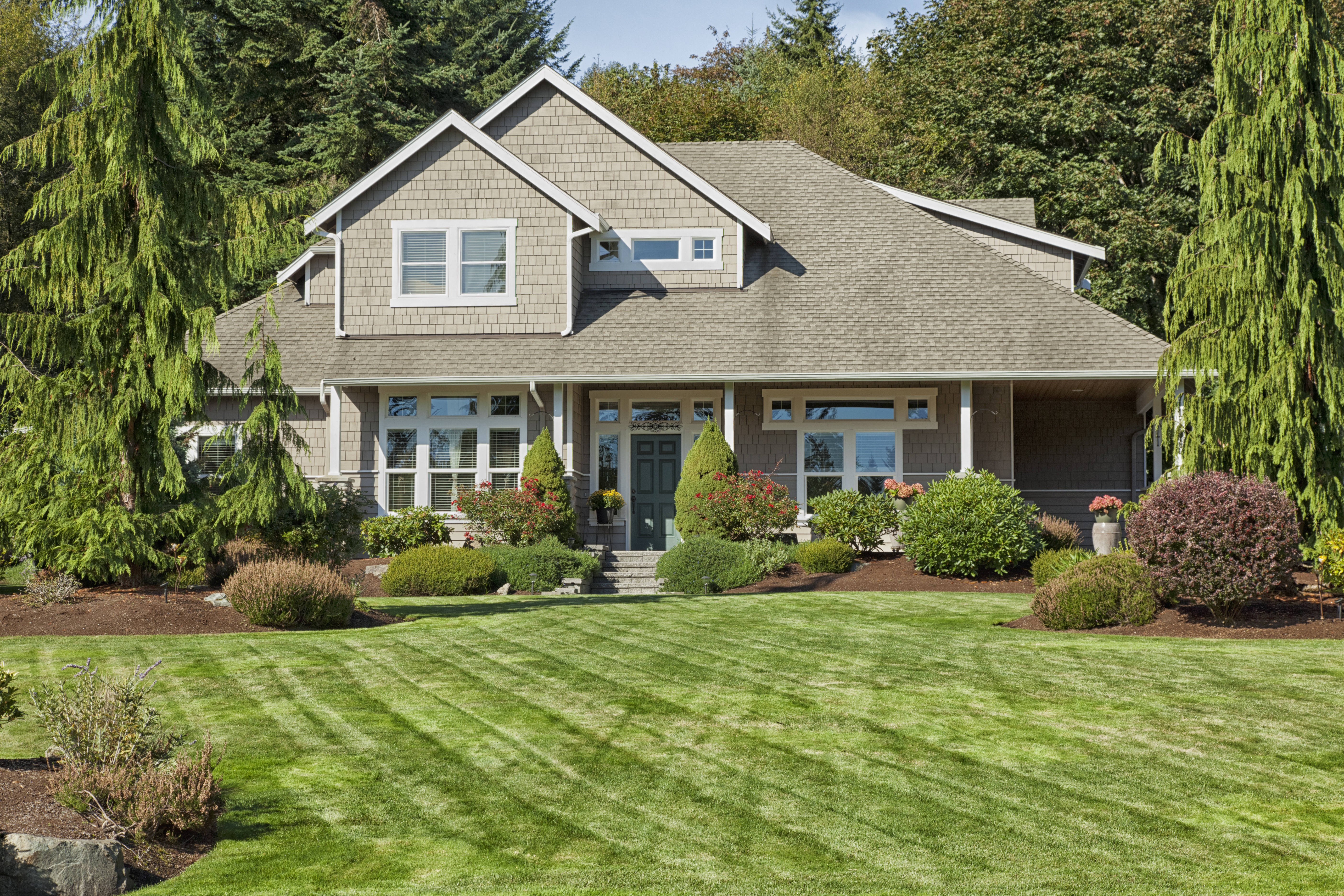 A two-story house with lawn and landscaped yard 