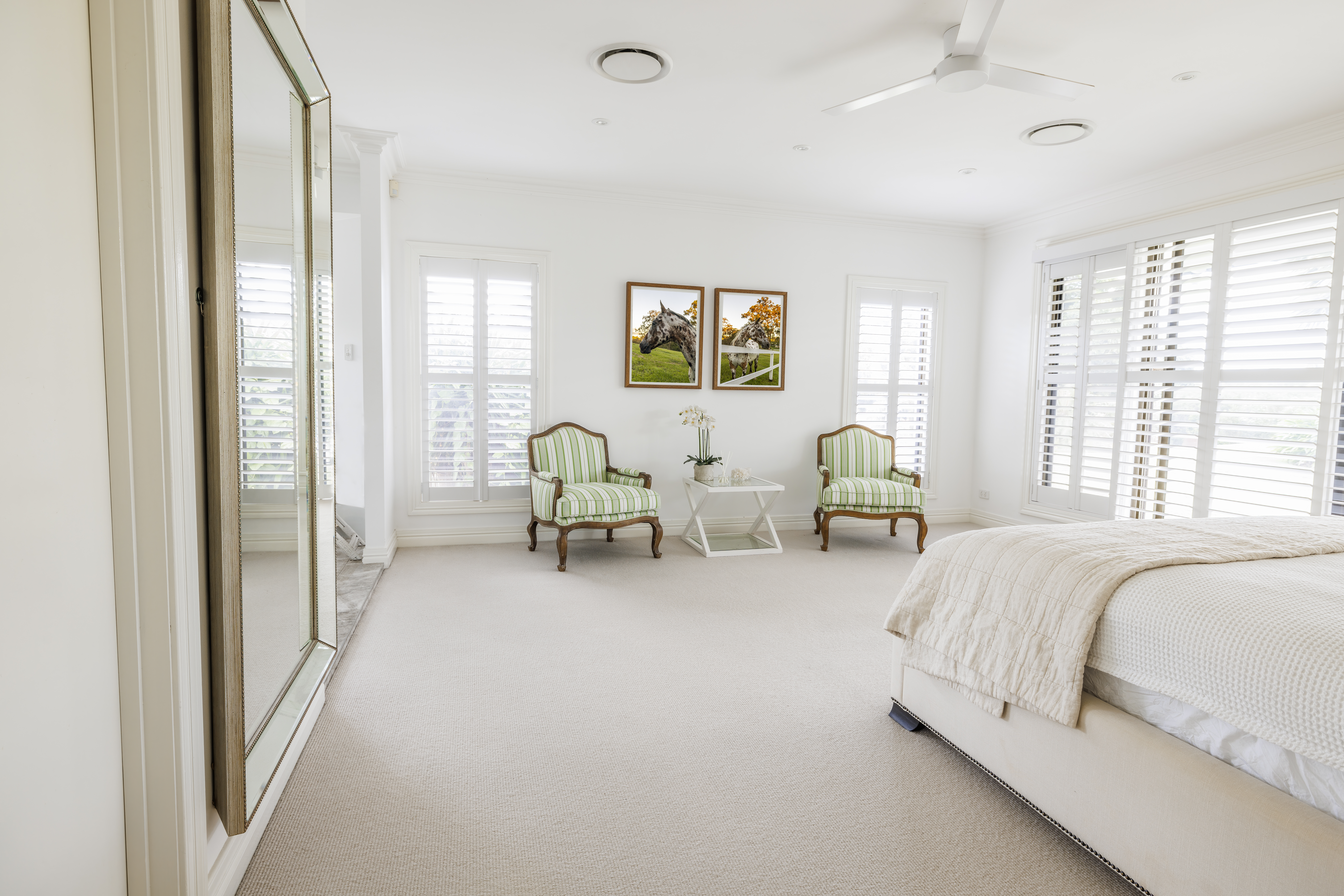 Bright primary bedroom with wool carpet and two green chairs