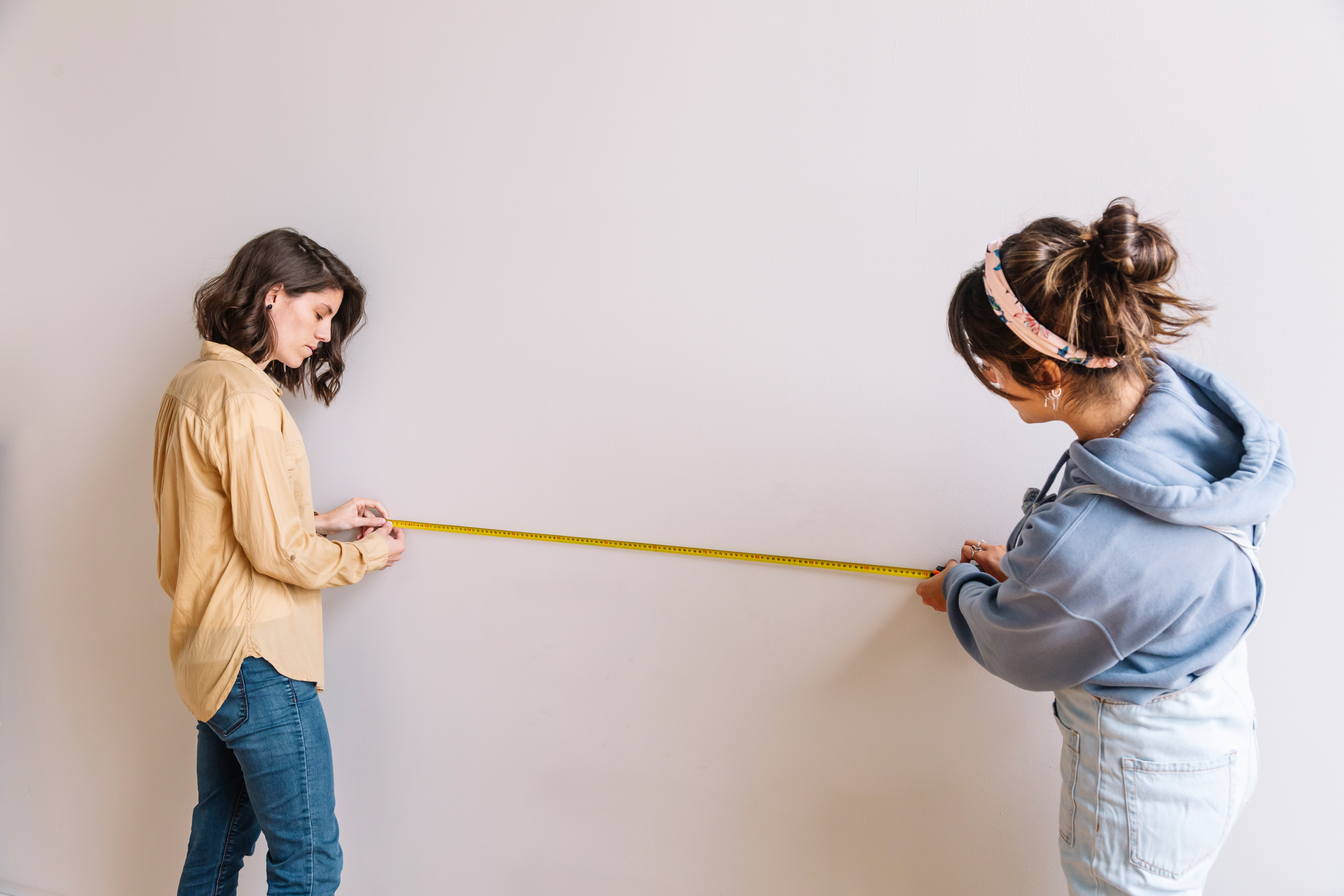 Two women measuring wall