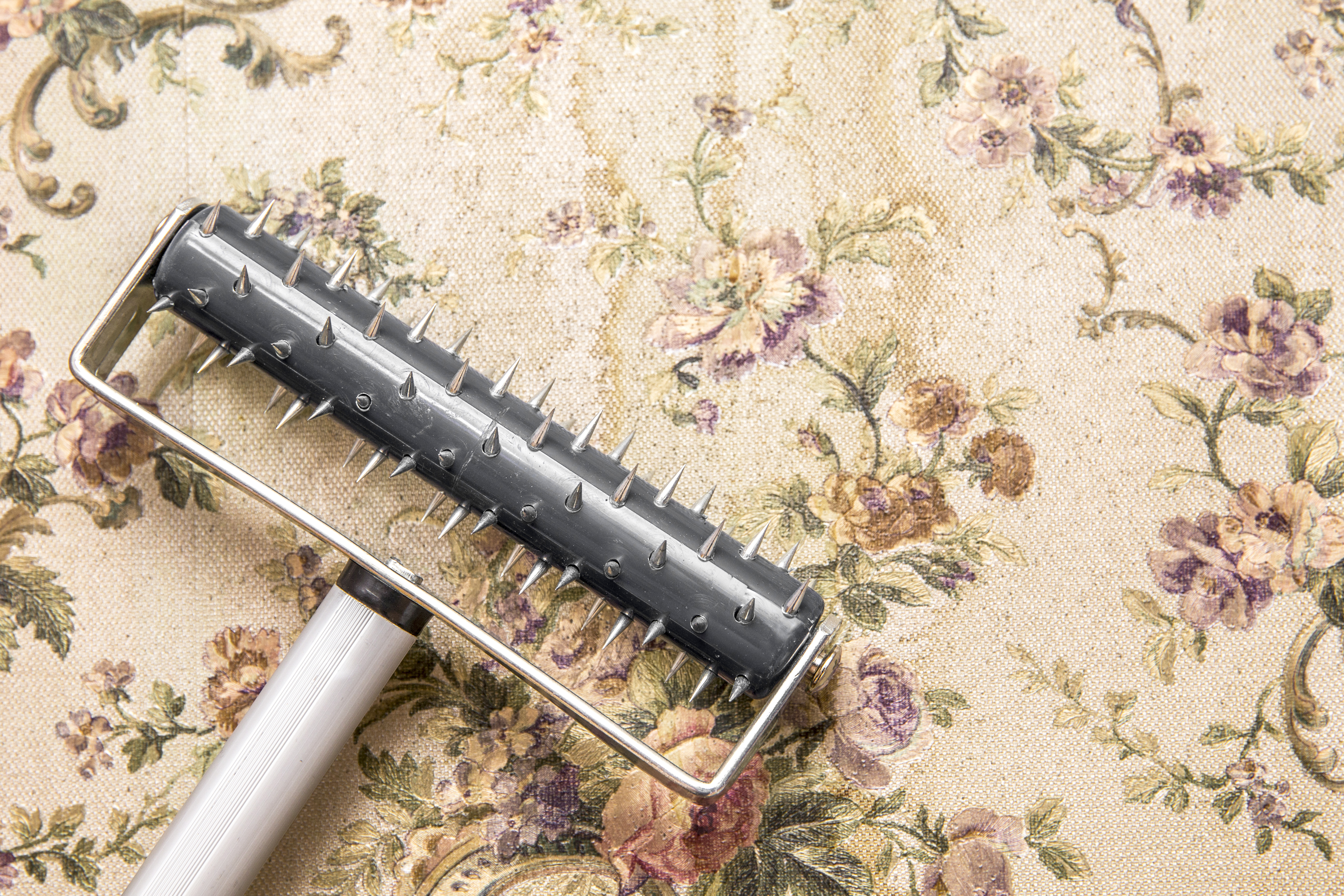 Using a scoring tool to remove old wallpaper from the wall