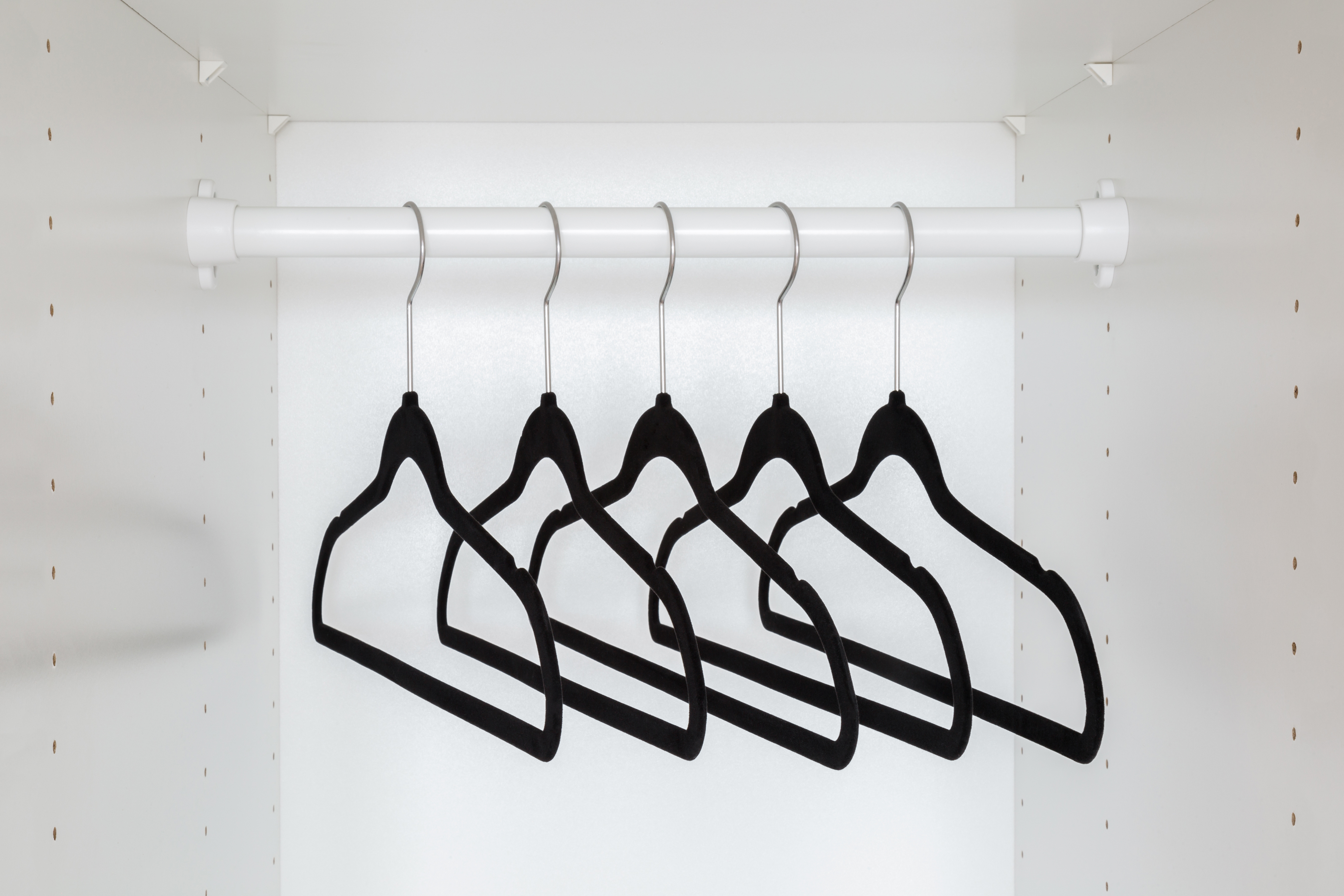 Dark black velvet empty hangers without clothes on rail
