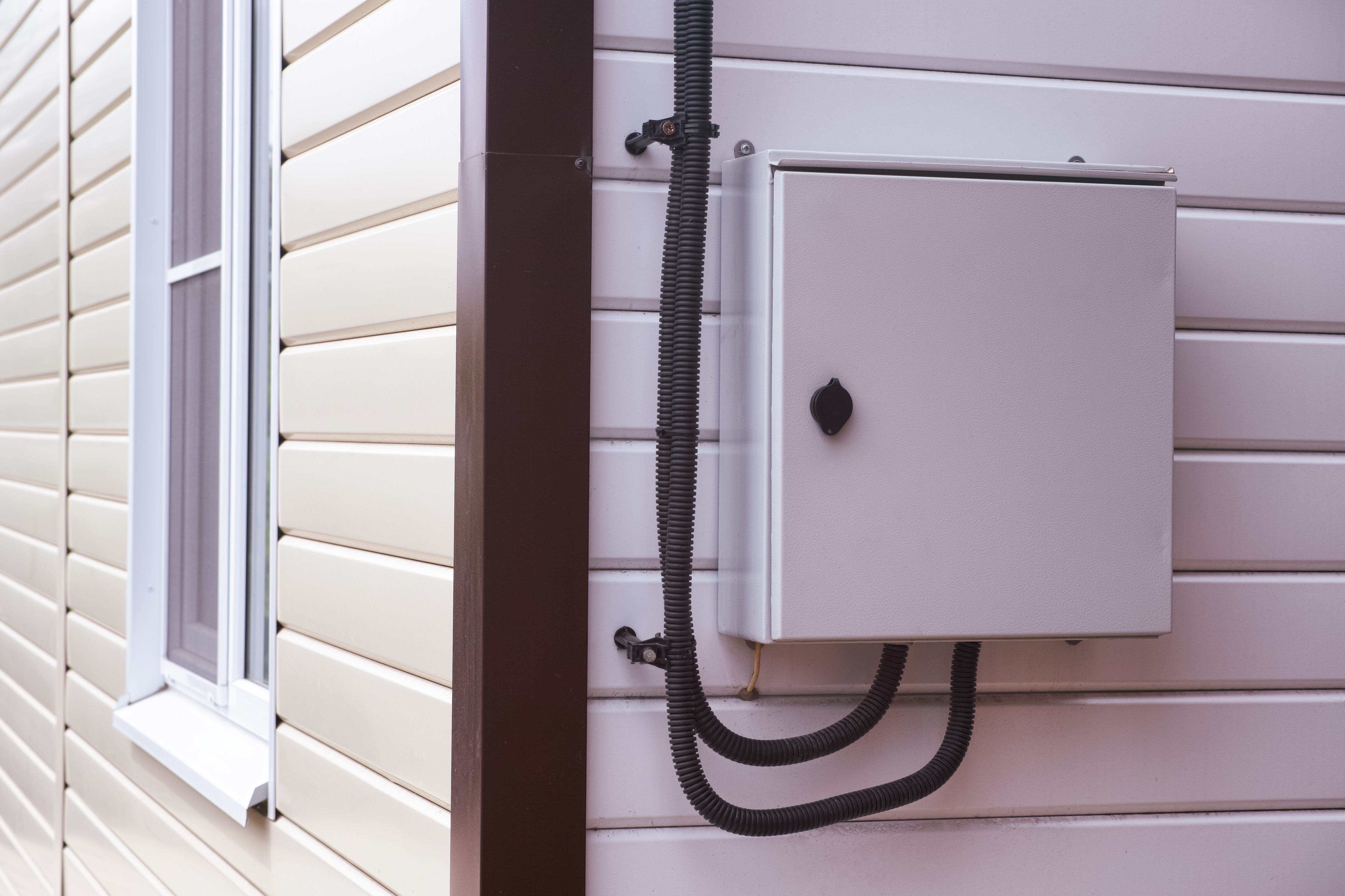An electrical box in a house with vinyl siding