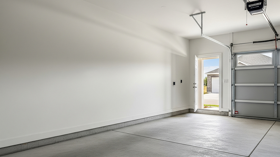 An empty, clean two-car garage with a concrete floor, a side door, and a partially open garage door