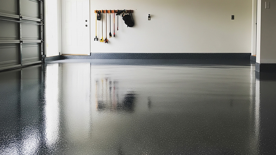 A pristine garage with gray epoxy flooring, white walls, and a door leading to the house