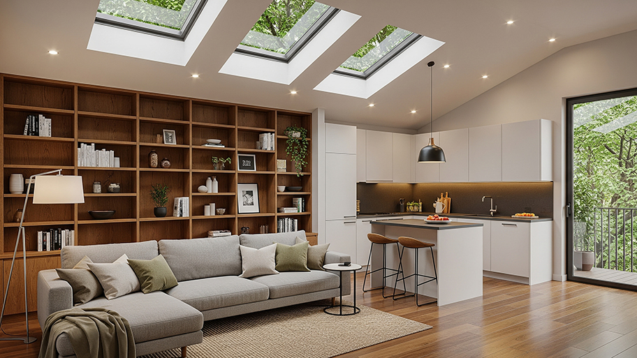 A modern open-plan room has a large bookcase, a kitchen, and a vaulted ceiling with skylights.