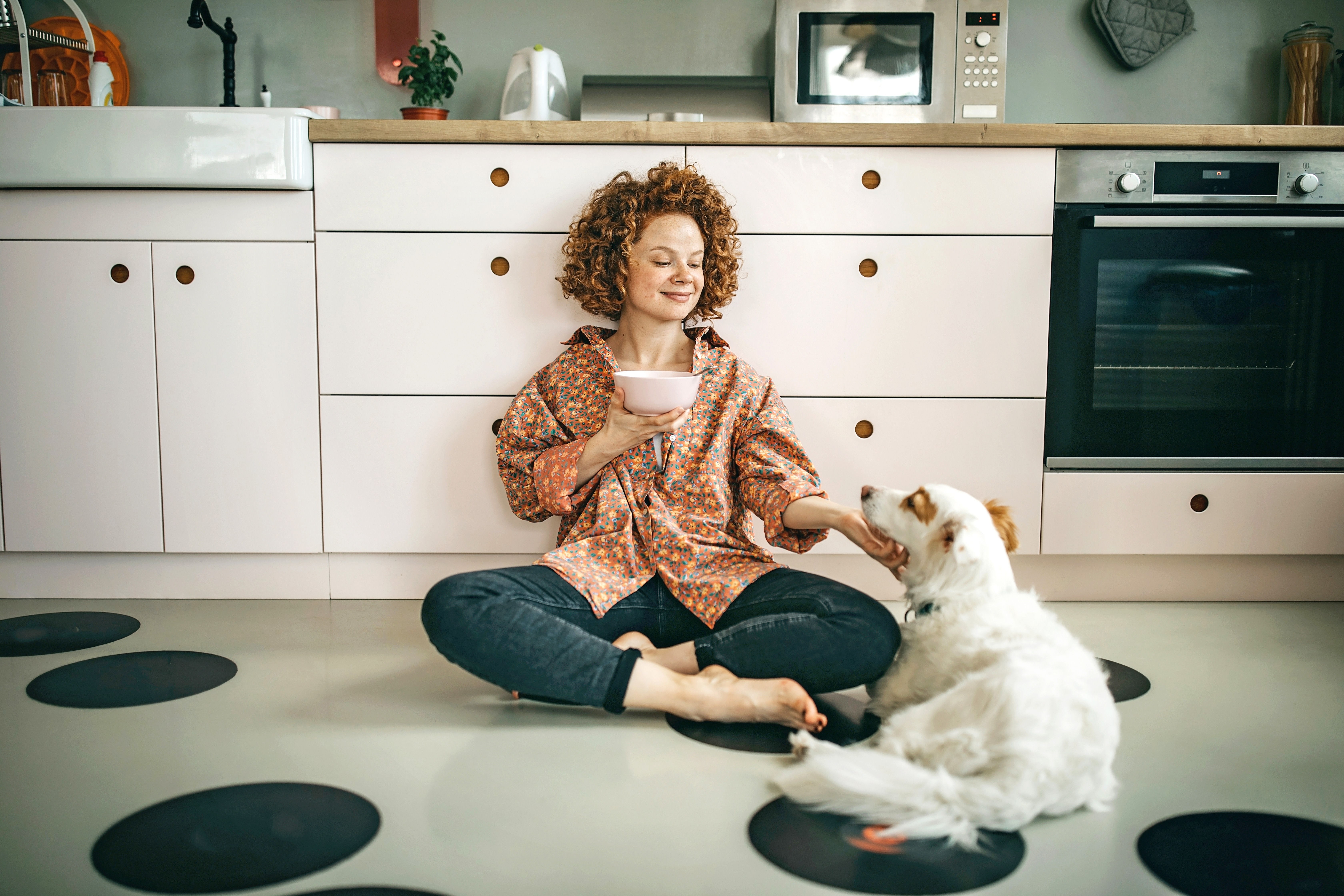 Woman and dog sitting on a vinyl floor and eating breakfast