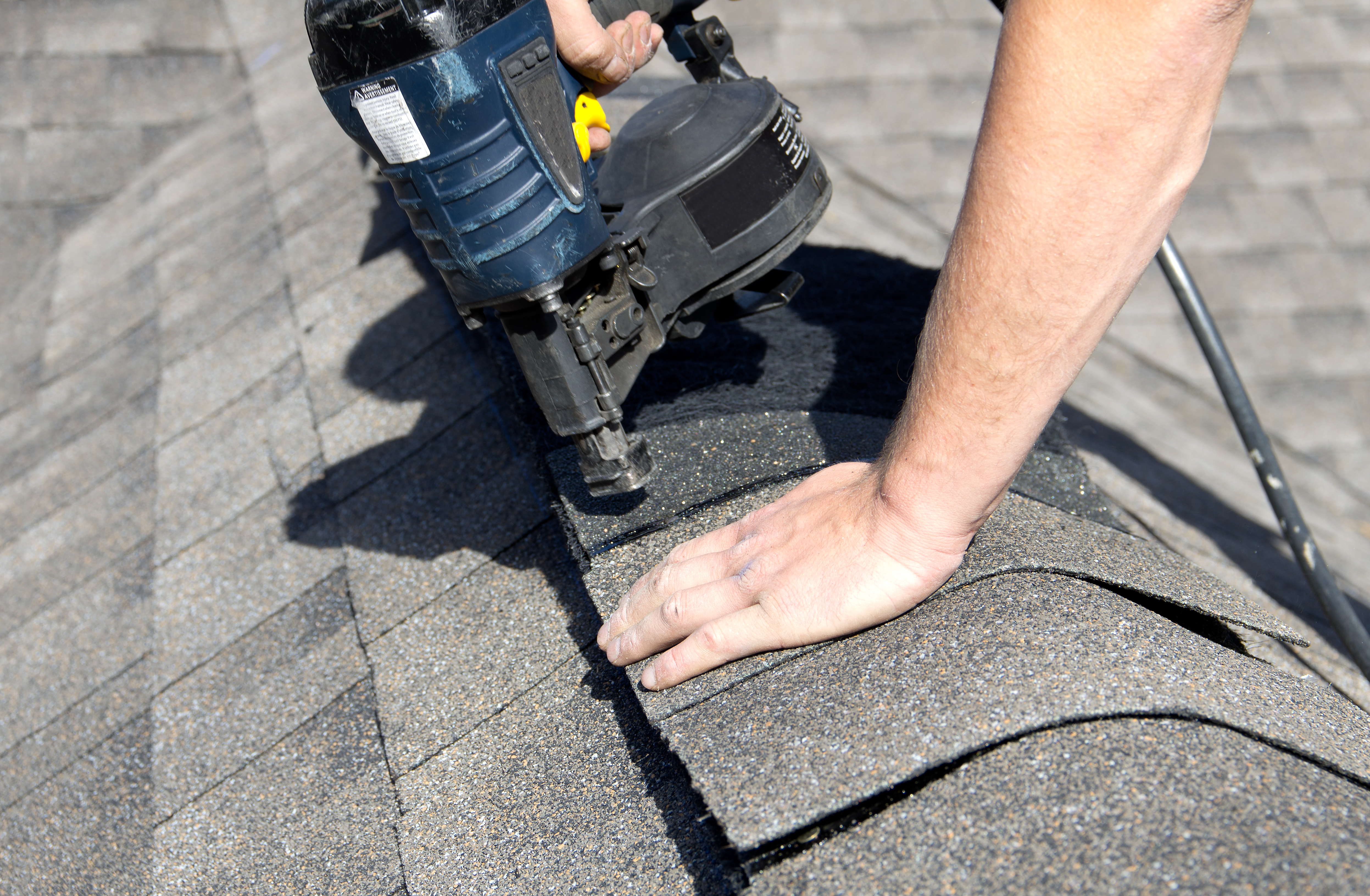 A person installing a roof ridge cap over the vent