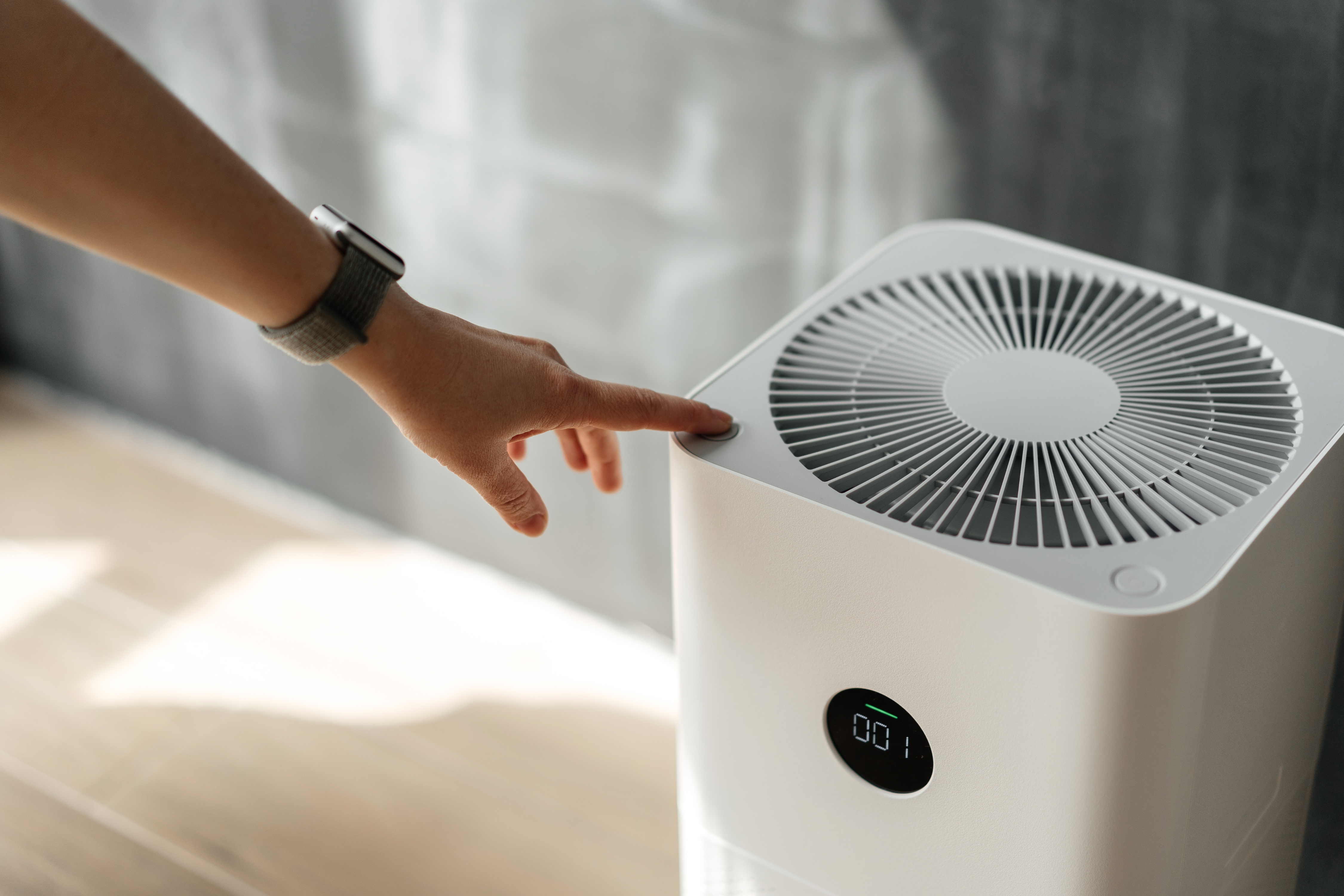 A person is pressing the power button on an air purifier