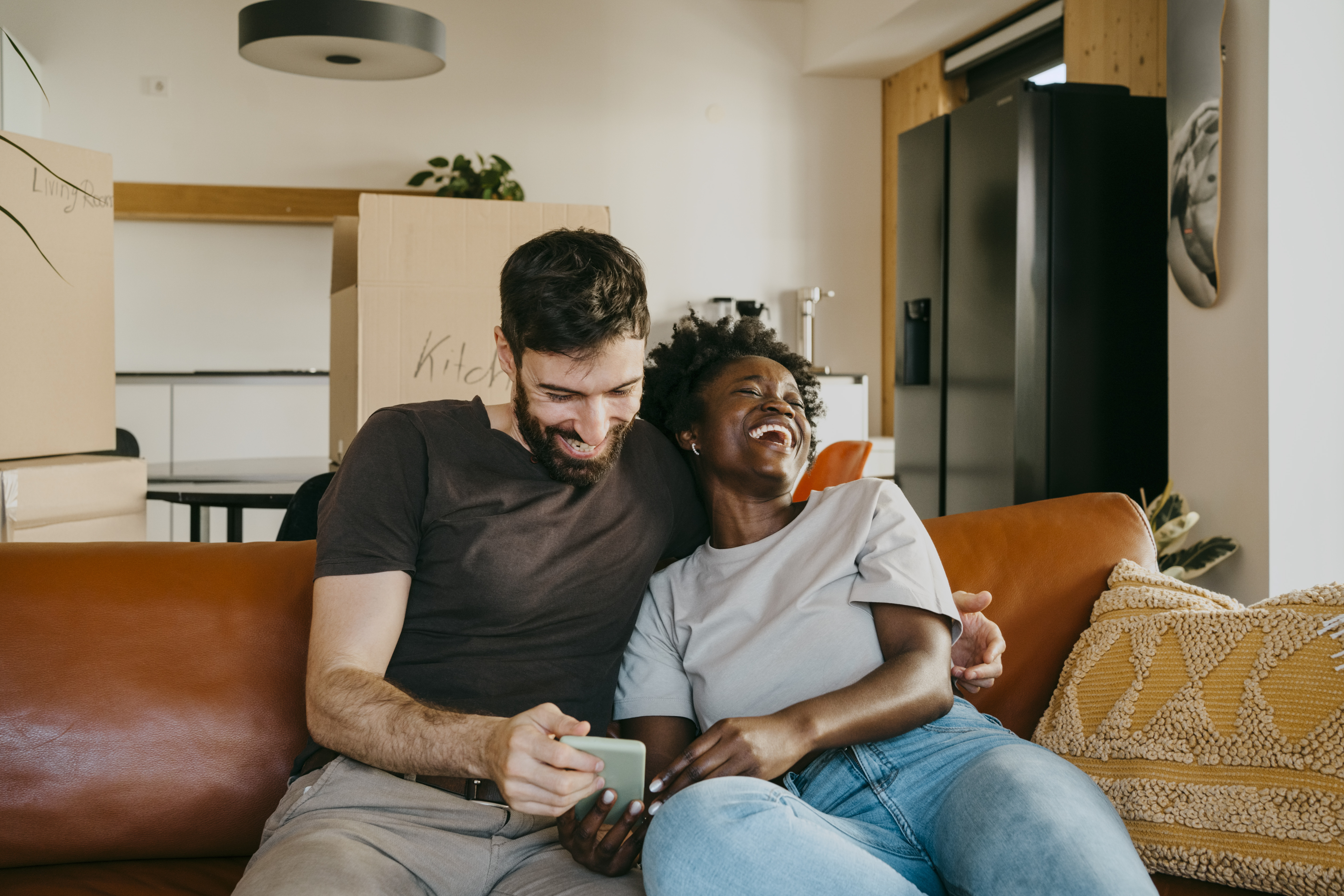 A couple enjoying sharing smart phone while sitting on sofa