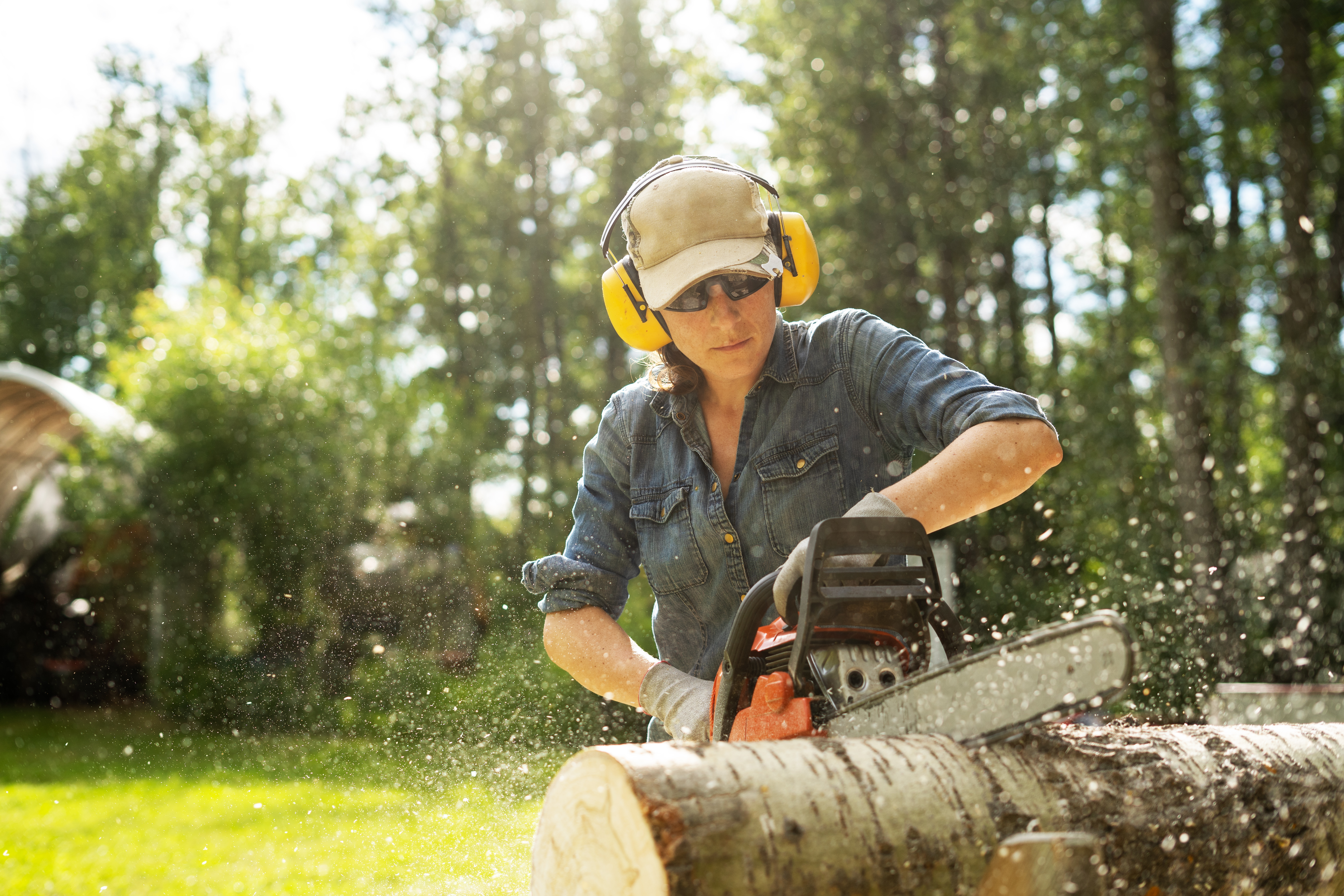 A woman cutting logs with a chainsaw
