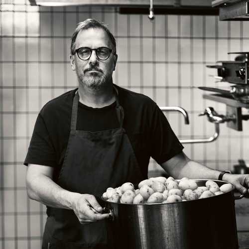 Stefan Ekengren med en stor kastrull med potatis, svartvit bild.