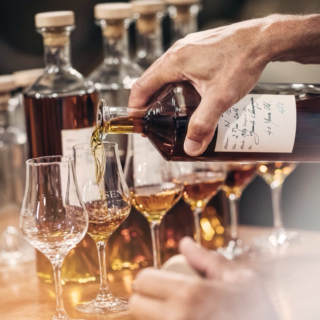 Gießen Sie Larsen Cognac aus einer alten Flasche in Gläser Gießen Sie Larsen Cognac aus einer alten Flasche in Gläser