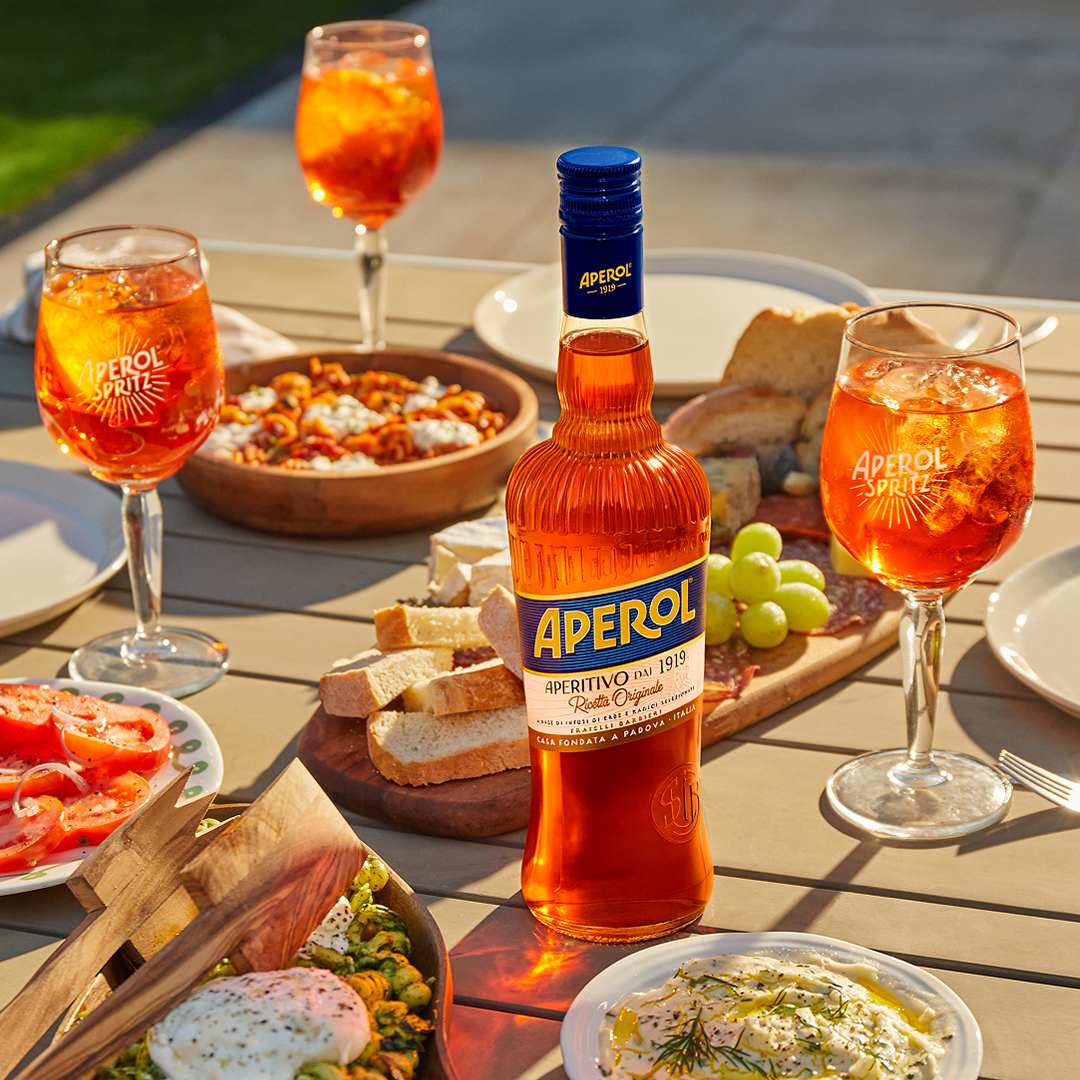 Aperol Spritz kokteil kokteiliklaasis jää, apelsiniviilu ja Aperoli pudeliga