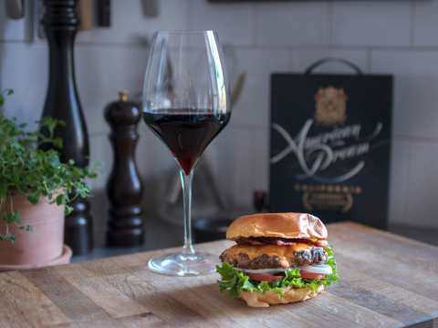 En hamburgare med bbq-sås och ett glas rött vin.