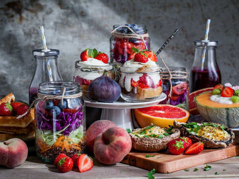 Brunch på ett bord med smoothie, grapefrukt, bär och jordgubbstrifle bland annat.