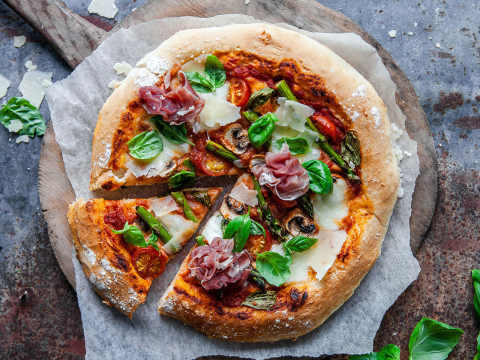 Hemgjord pizza på pizzaspade på ett bord.
