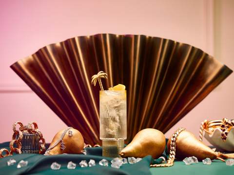 Högt cocktailglas framför en solfjäder