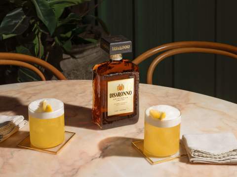 Disaronno Sour med en flaska Disaronno i bakgrunden