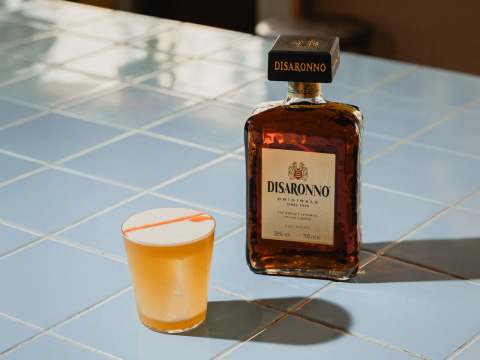 Disaronno Sour med en flaska Disaronno i bakgrunden
