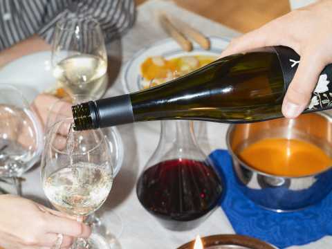 viinipullosta_kaadetaan_lasiin_ruokapöydässä