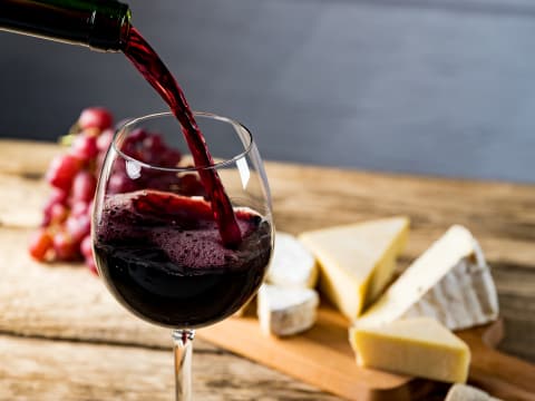 punaviiniä_kaadetaan_lasiin_ja_taustalla_juustoja