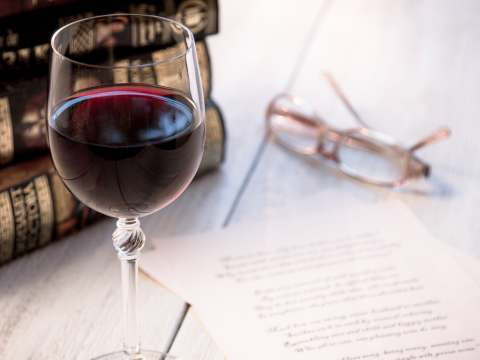 punaviinilasi_vaalealla_pöydällä_ja_kirjoja