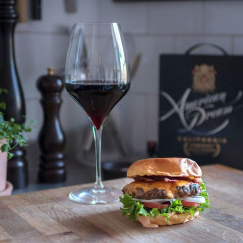 En hamburgare med bbq-sås och ett glas rött vin.
