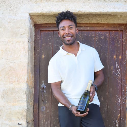 John Lundvik mot en brun dörr till ett stenhus i Bourgogne.