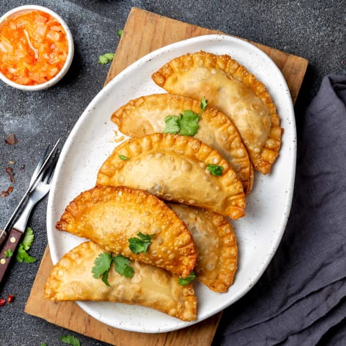 Empanadas med kyckling på vit tallrik.