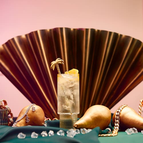 Högt cocktailglas framför en solfjäder