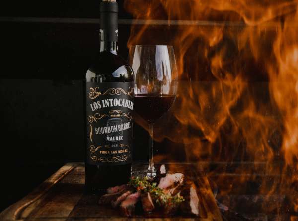 los_intocables_bourbon_barrel_punaviinipullo_pöydällä_ja_tulenlieskoja