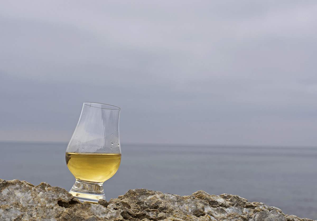 Whiskyglas på en klippa med utsikt över havet